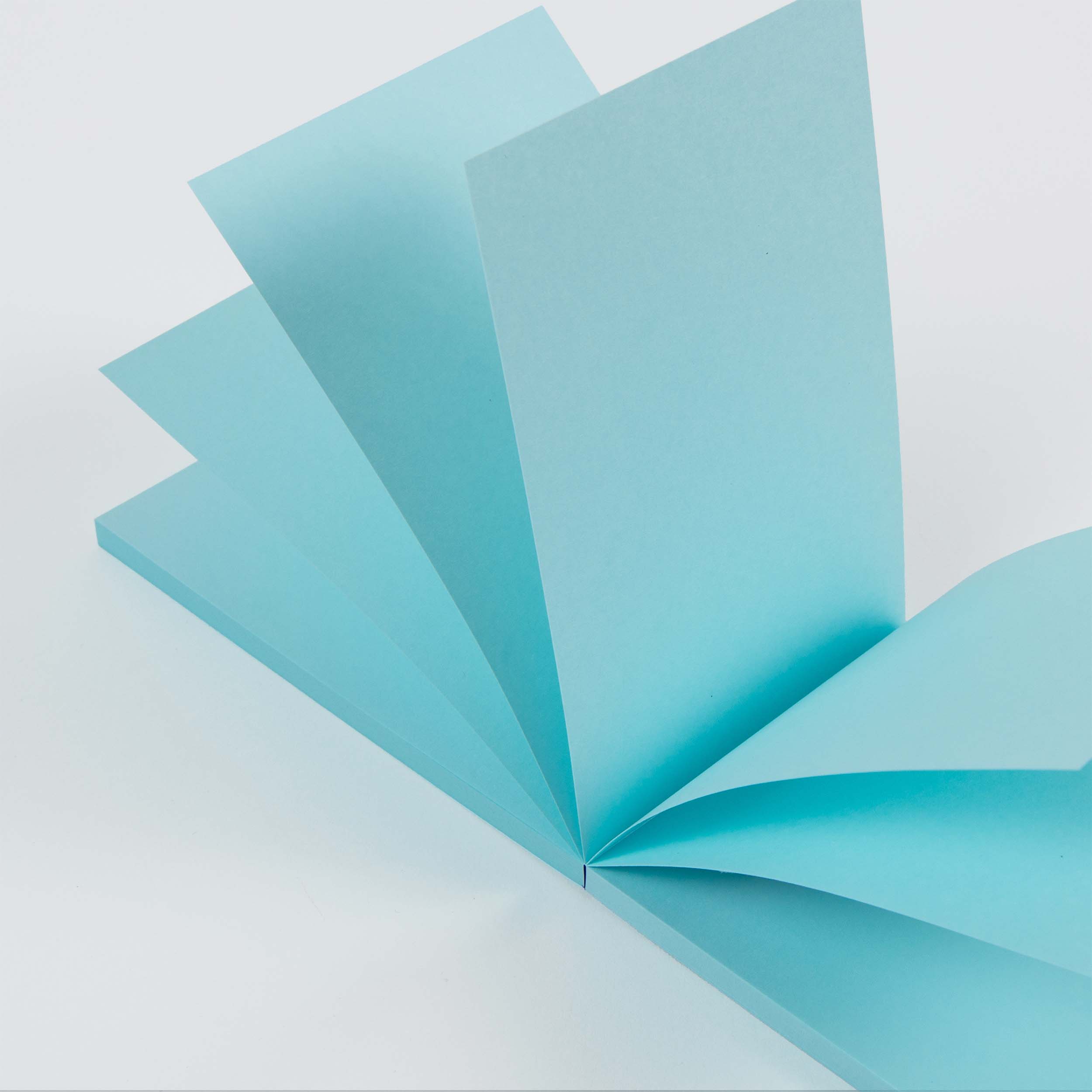 Ein Stapel Paperlux Abreissblöcke Neon in Hellblau, teilweise aufgefächert und aufrecht auf einer weißen Fläche stehend, bildet ein markantes geometrisches Muster.