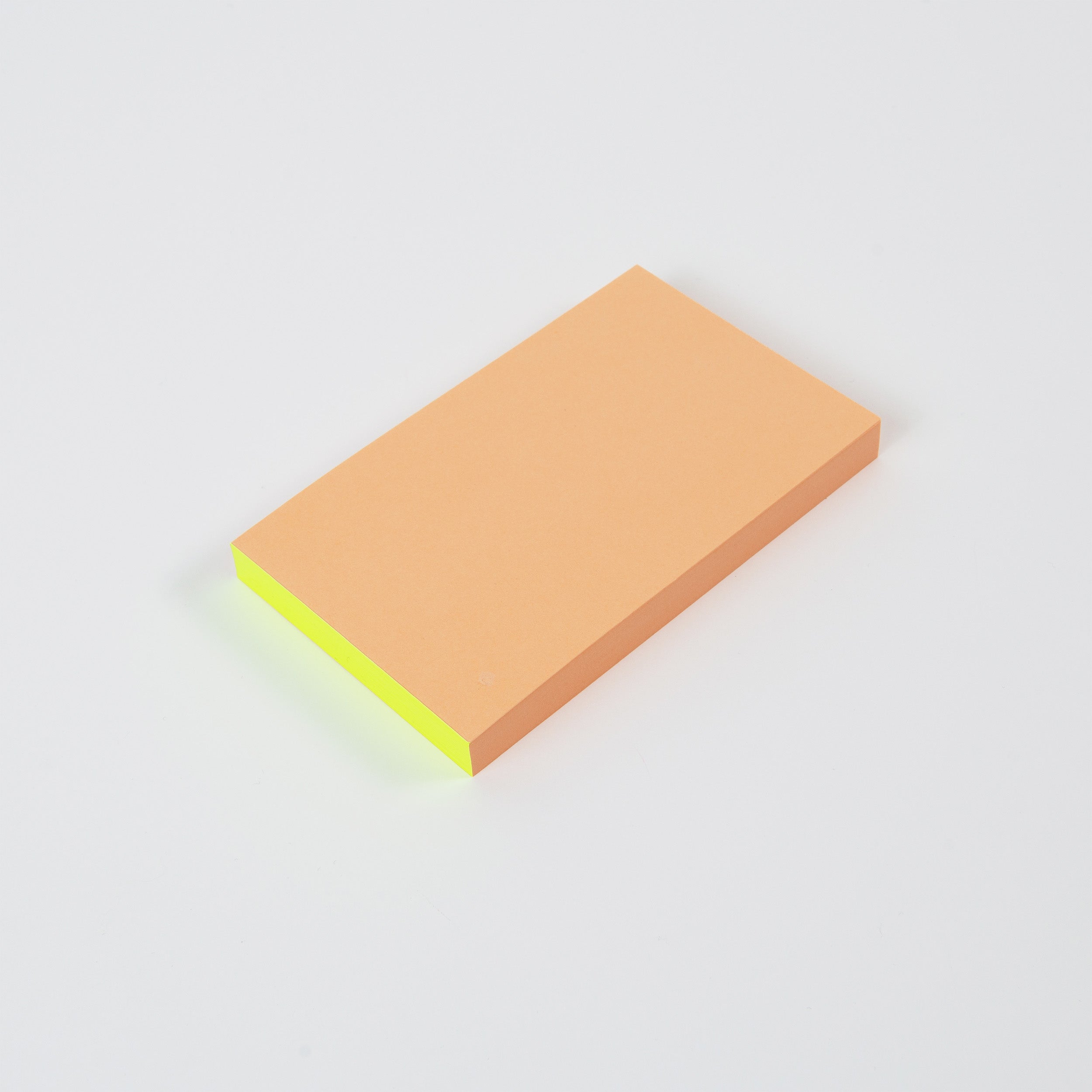 Die paperlux Abreissblöcke Neon sind ein rechteckiger Stapel Haftnotizen aus Feinstpapier-Resten, mit einem orangefarbenen oberen Blatt und gelben Blättern darunter, dargestellt auf weißem Hintergrund.