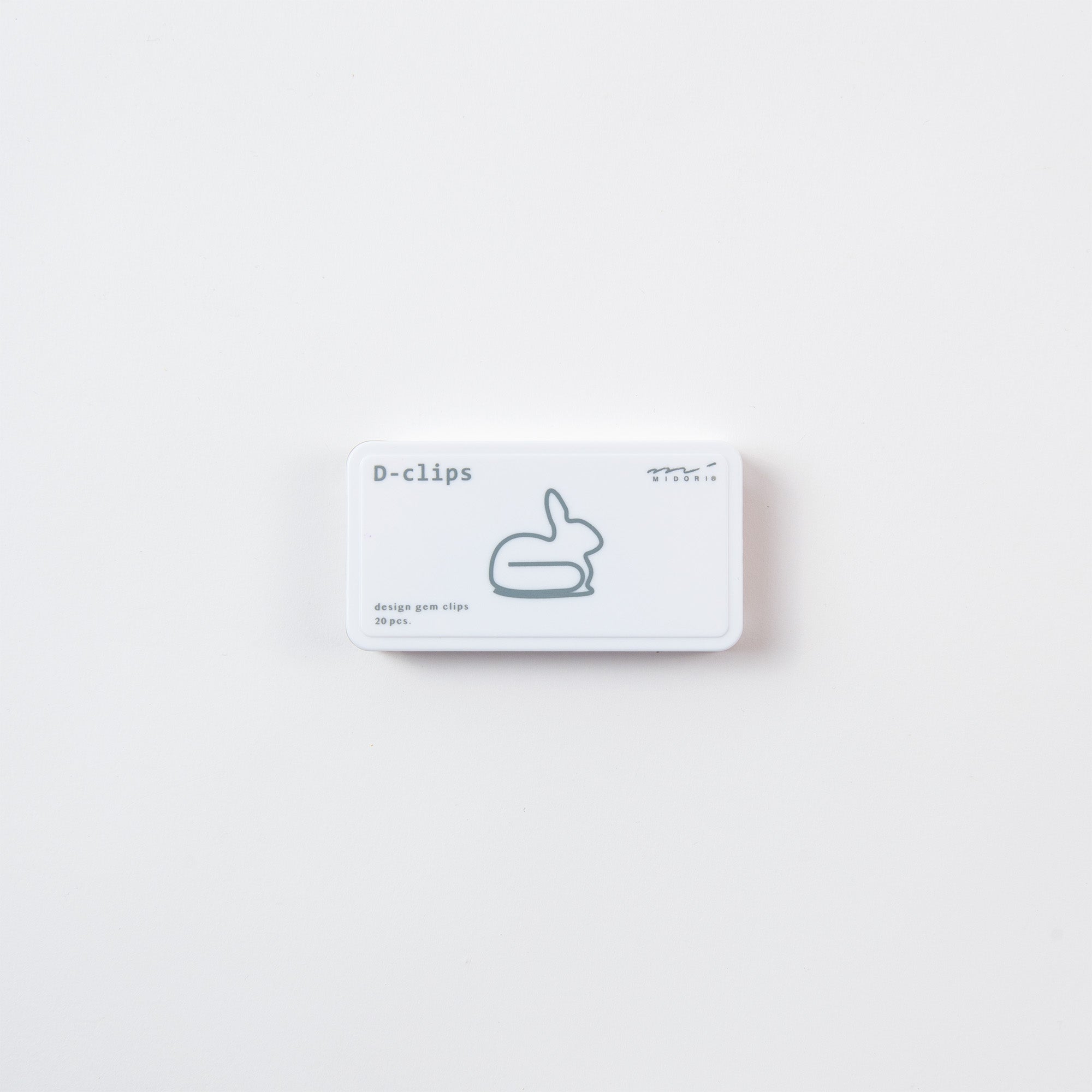 Eine kleine weiße Schachtel mit D-Clips von Midori mit Büroklammern in Hasenform und einer minimalistischen Enten-Strichzeichnung auf dem Deckel verströmt vor einem schlichten weißen Hintergrund den charmanten japanischen Klammern-Stil.