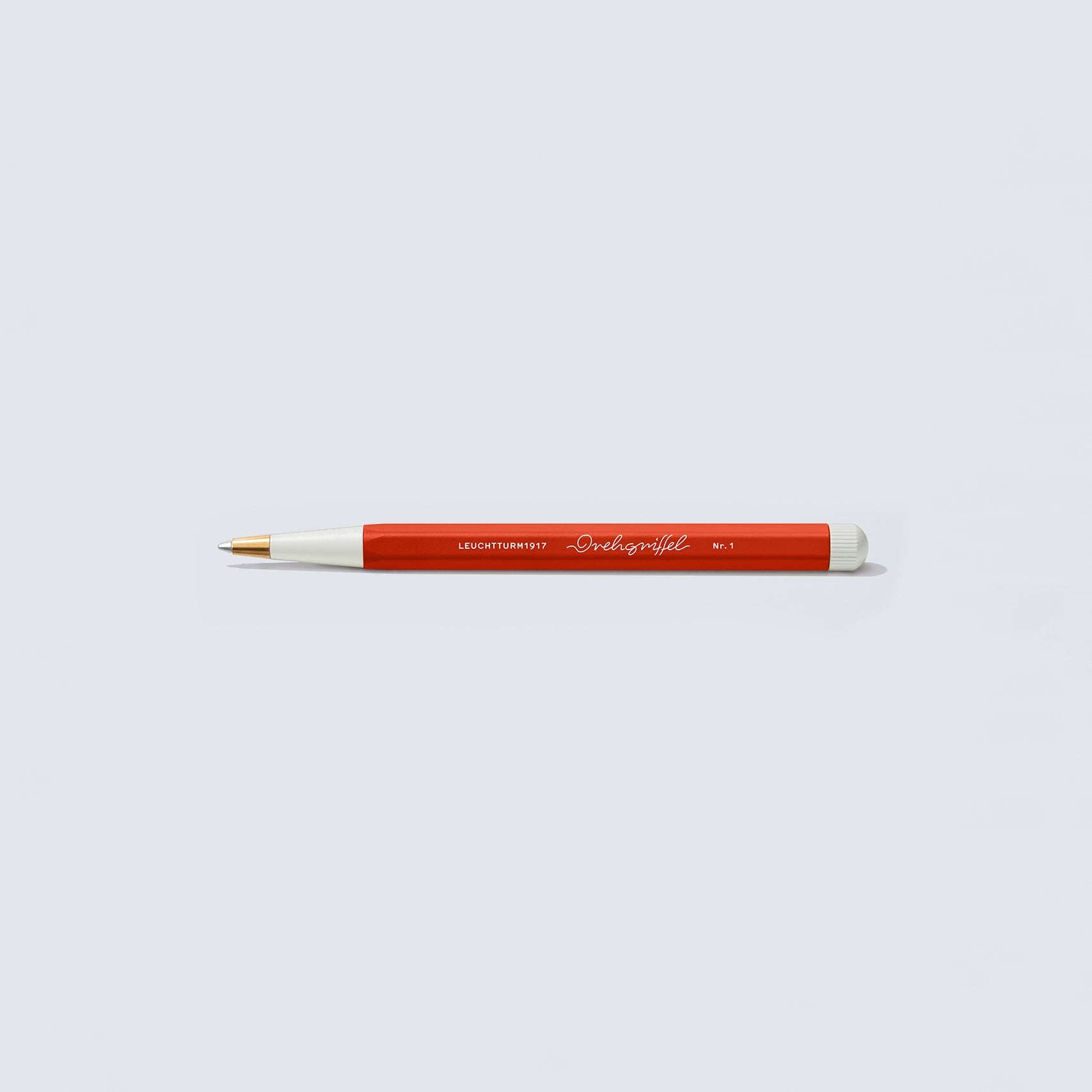 Der Leuchtturm 1917 Drehgriffel Nr. 1, ein rot-weißer Stift mit goldener Spitze, liegt horizontal auf einem hellgrauen Hintergrund und zeigt mit seiner schlanken Form und den raffinierten Details elegantes Produktdesign.