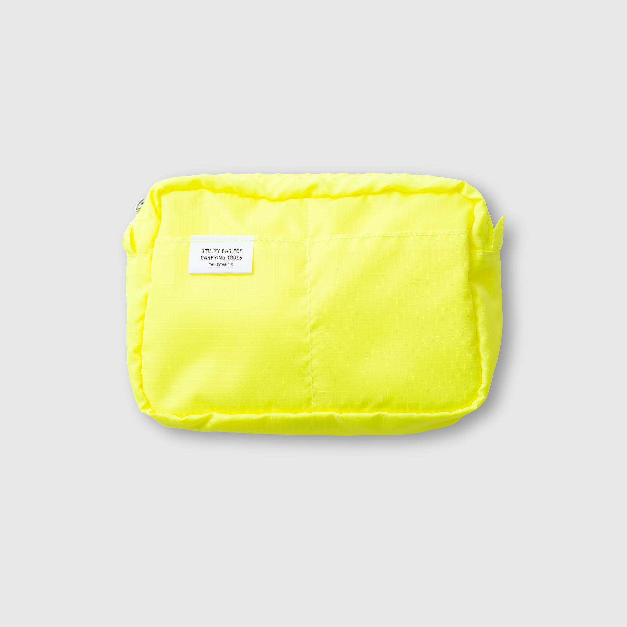 Eine leuchtend gelbe Delfonics Inner Carrying Case AIR S aus strapazierfähigem Ripstop-Gewebe mit einem kleinen weißen Etikett auf der Vorderseite dient als stilvolle Notizbuchtasche und wird hier vor einem schlichten hellgrauen Hintergrund gezeigt.