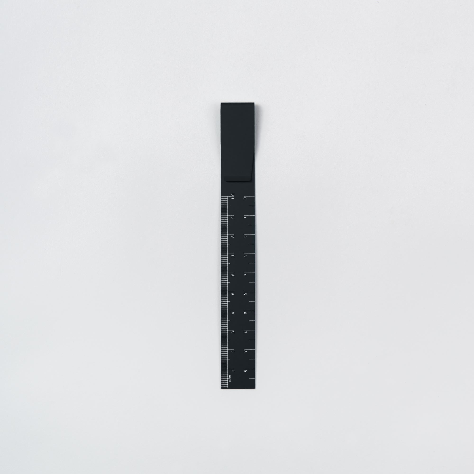 Das schwarze Clip Ruler - das Lineal To Go von Hightide steht vertikal vor einem weißen Hintergrund und verfügt über deutlich markierte weiße Linien für präzises Messen, ideal für Bullet-Journal-Fans, die Wert auf Organisation und Kreativität legen.
