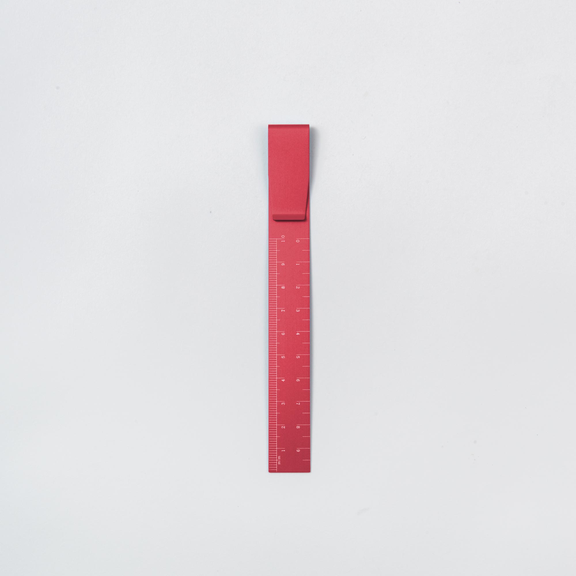 Ein leuchtend rotes Clip Ruler - das Lineal To Go von Hightide, ausgestattet mit Zentimetermarkierungen, steht vertikal auf einem schlichten weißen Hintergrund. Ideal für Ihr Bullet Journal oder als originelles Lesezeichen, verbindet es Stil und Funktionalität nahtlos.