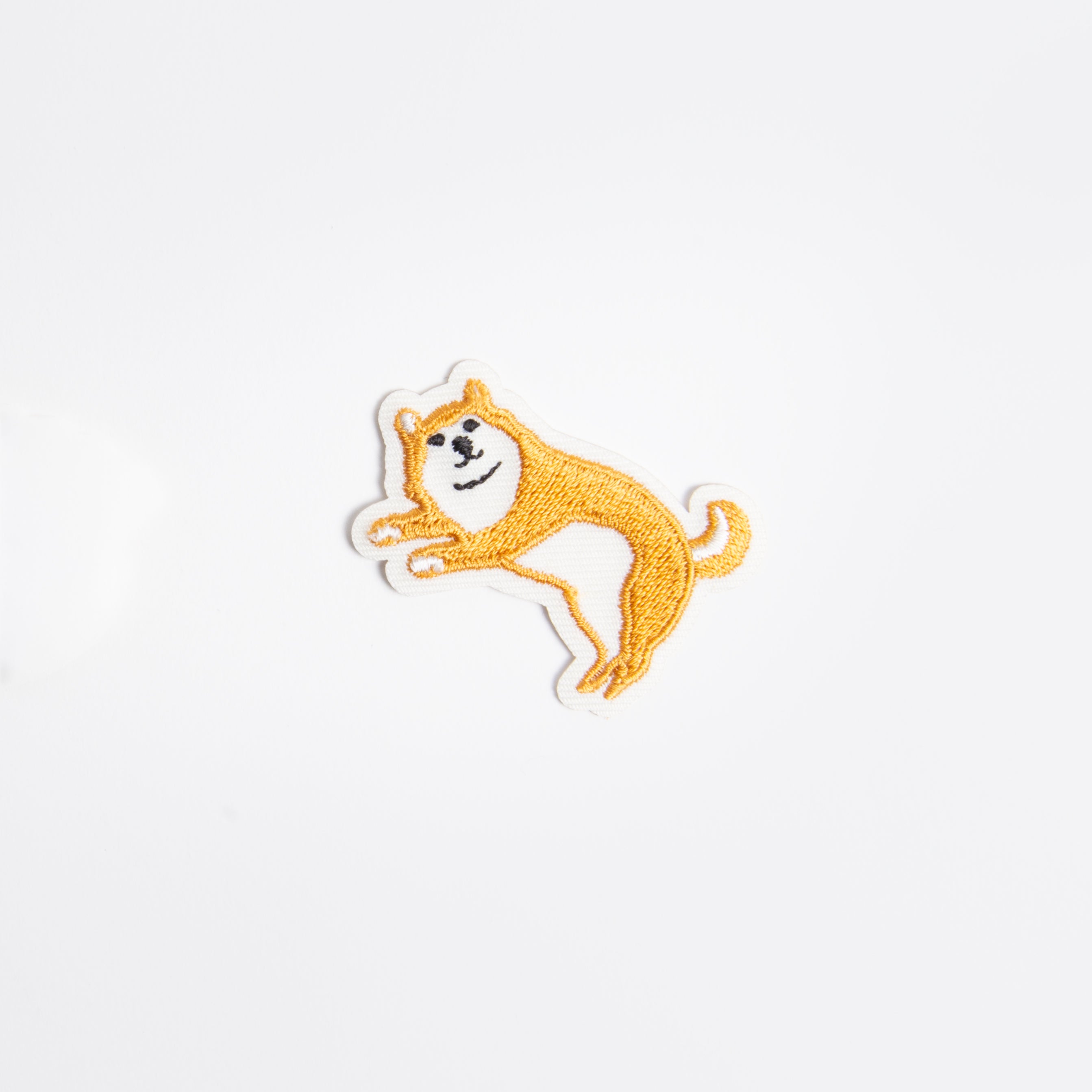 Der Hightide New Retro Patch Sticker zeigt einen fröhlichen, orange-weißen Hund im Cartoon-Stil mit gespitzten Ohren auf weißem Hintergrund, der verspielte Retro-Vibes einfängt. Marke: Hightide.