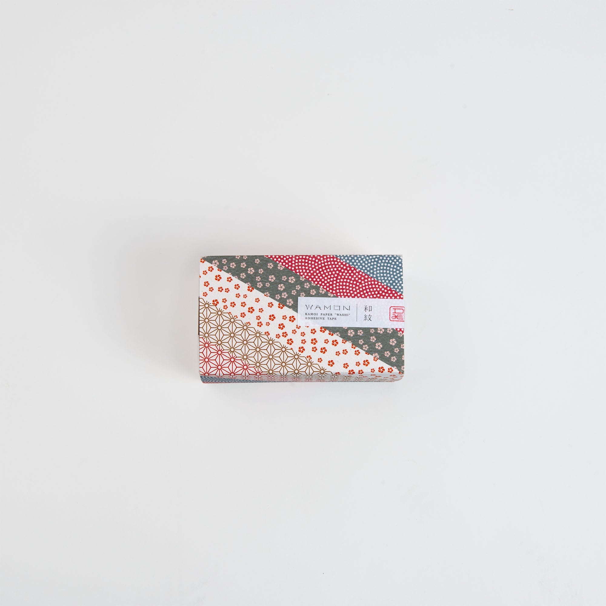 Die Kamoi Kakoshi mt Washi Tape - Wamon 5 Geschenkbox ist eine kleine rechteckige Box mit bunten, japanisch gemusterten Streifen in Rot, Blau, Gold und Weiß und einem weißen Etikett mit japanischem Text auf der Oberseite vor einem schlichten weißen Hintergrund.