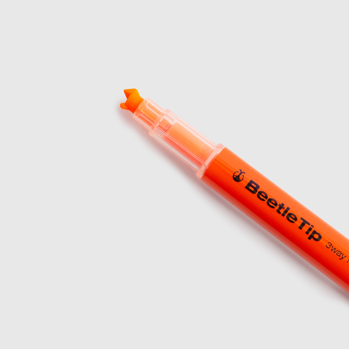 Ein Kokuyo Beetletip 3-Way Highlighter – Textmarker mit 3 Spitzen in Orange, mit einer charakteristischen, keilförmigen Spitze, abgebildet auf einem schlichten hellgrauen Hintergrund.