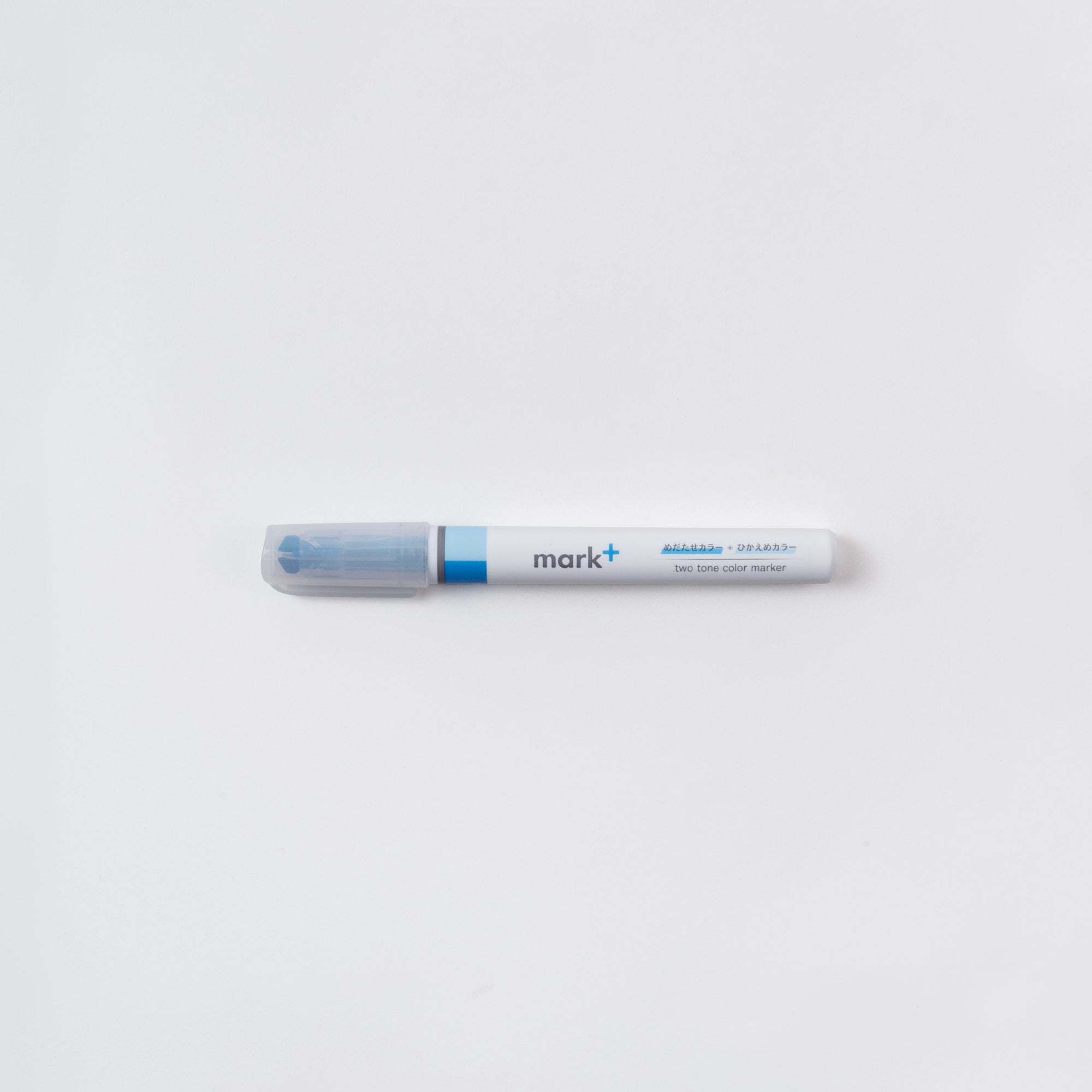 Ein Kokuyo Ein (Text-) Marker, Zwei Farben mit blauem Schaft und transparenter Kappe liegt waagerecht auf weißem Untergrund. Der mit „mark+“ gekennzeichnete Stift verfügt über eine Meißelspitze für präzises Schreiben.