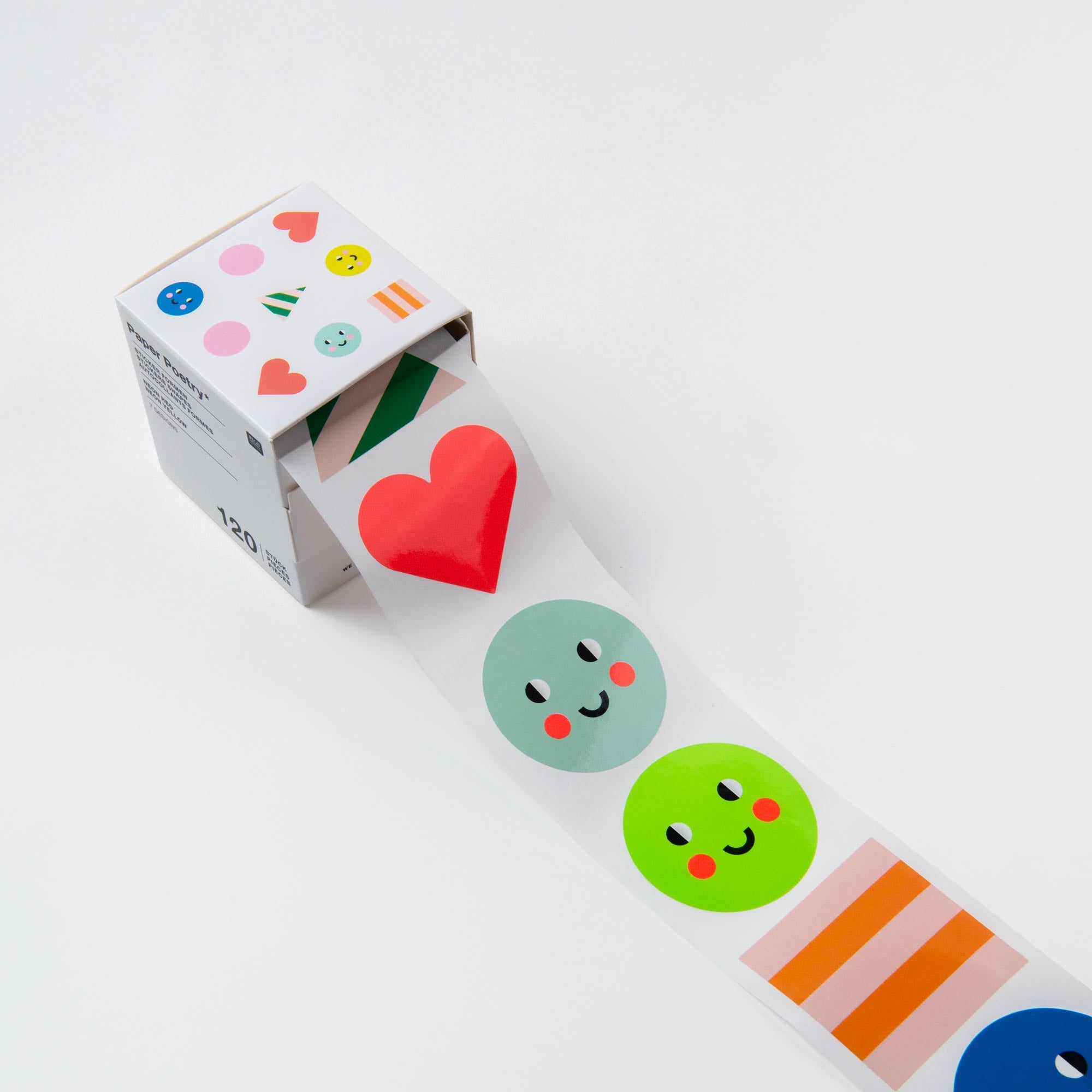 Eine Rolle des Paper Poetry „Sticker Set – 7 Mal Fröhlichkeit“ entfaltet sich in einer weißen Box, die mit fröhlichen Motiven verziert ist. Mit Smileys, Herzen, geometrischen Formen, grünen Kreisen, einem roten Herz und Streifenmustern verleihen diese Sticker jedem Geschenk eine verspielte „Happy Birthday“-Note.