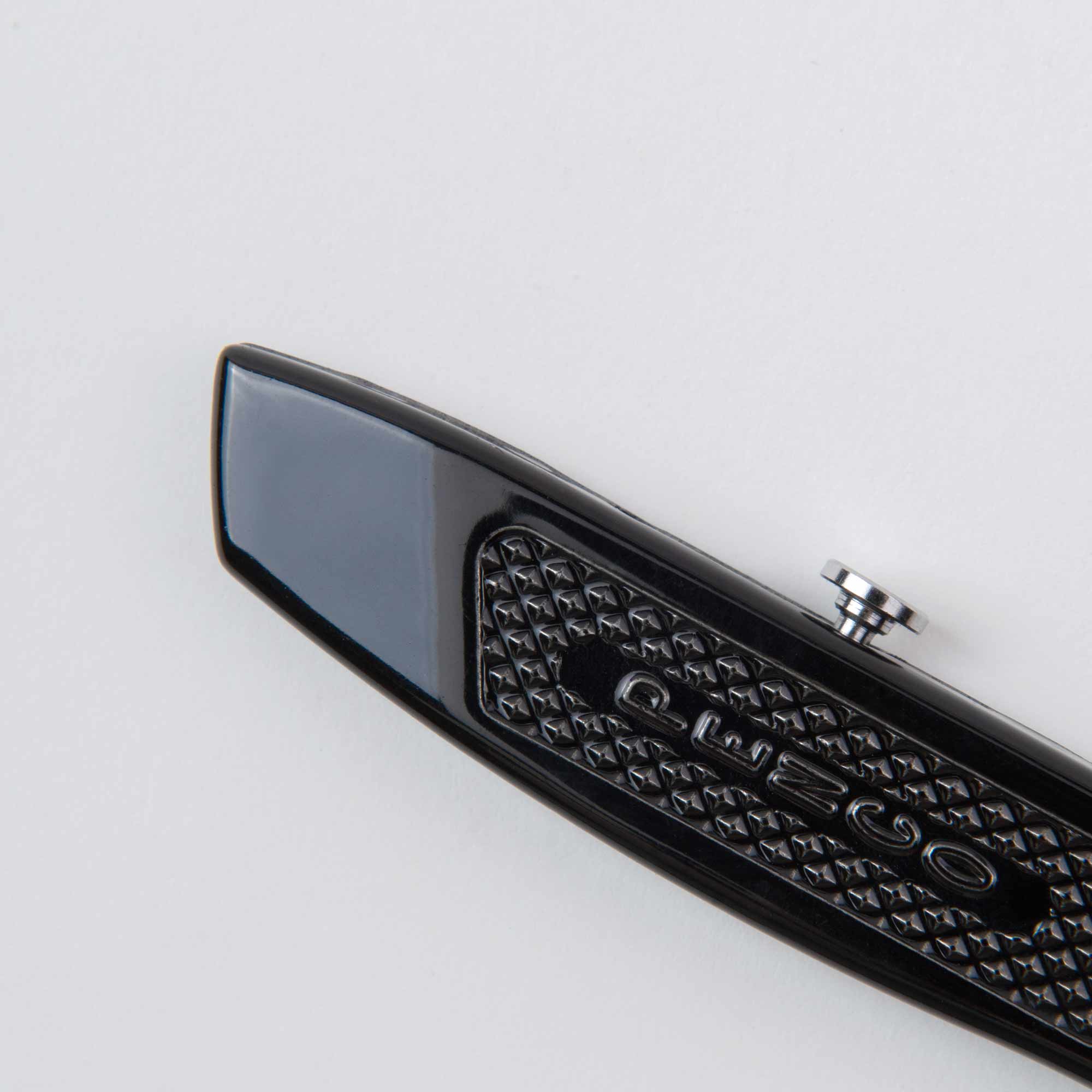 Nahaufnahme des Allzweckmesser-Cutters von Penco mit elegantem schwarzen Design, strukturiertem Griff und kleinem Metallknopf. Er zeigt eingravierte Buchstaben auf einer geometrischen Oberfläche, die an ein Ersatzklingen-Finish erinnert, vor einem schlichten weißen Hintergrund.