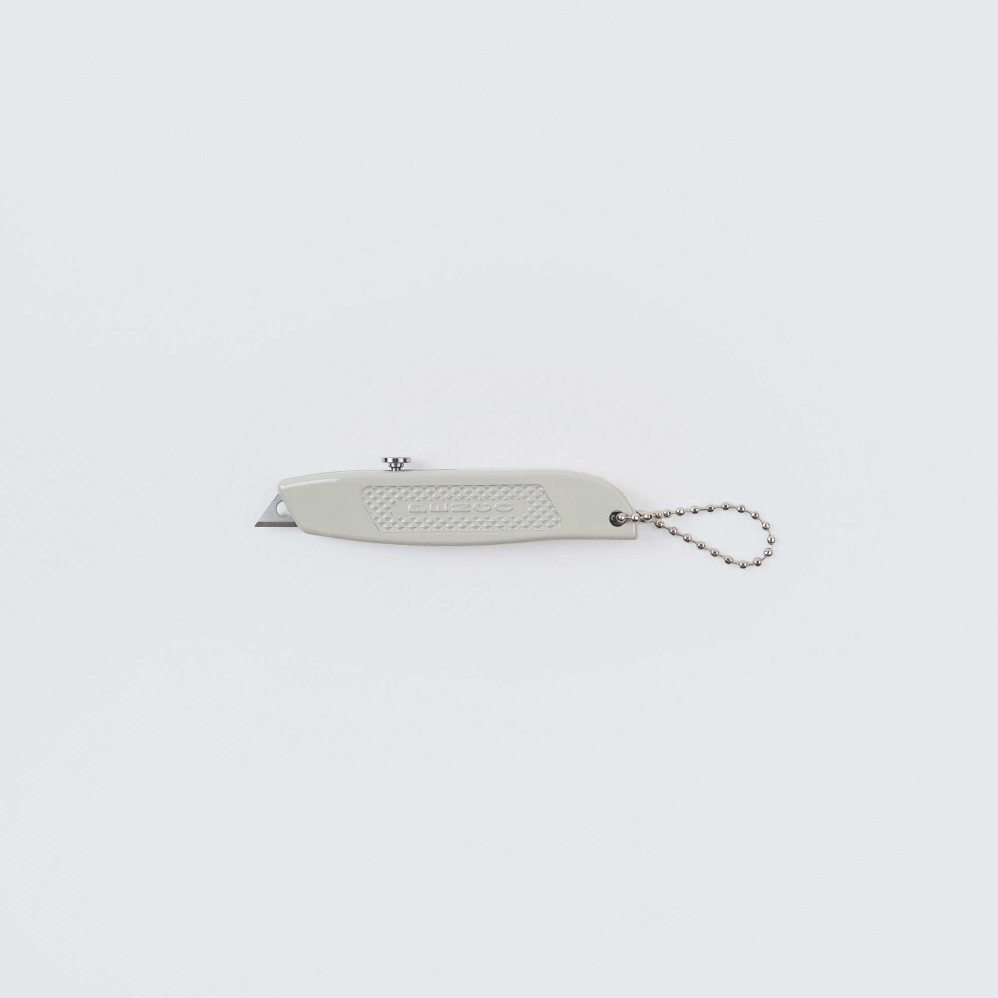 Das Penco Allzweckmesser, auch bekannt als der Cutter an der Kette, ist ein kleines, hellgraues Messer mit Ersatzklingen und griffiger Oberfläche-ideal zum Pakete öffnen. Es liegt auf schlichtem weißem Hintergrund.