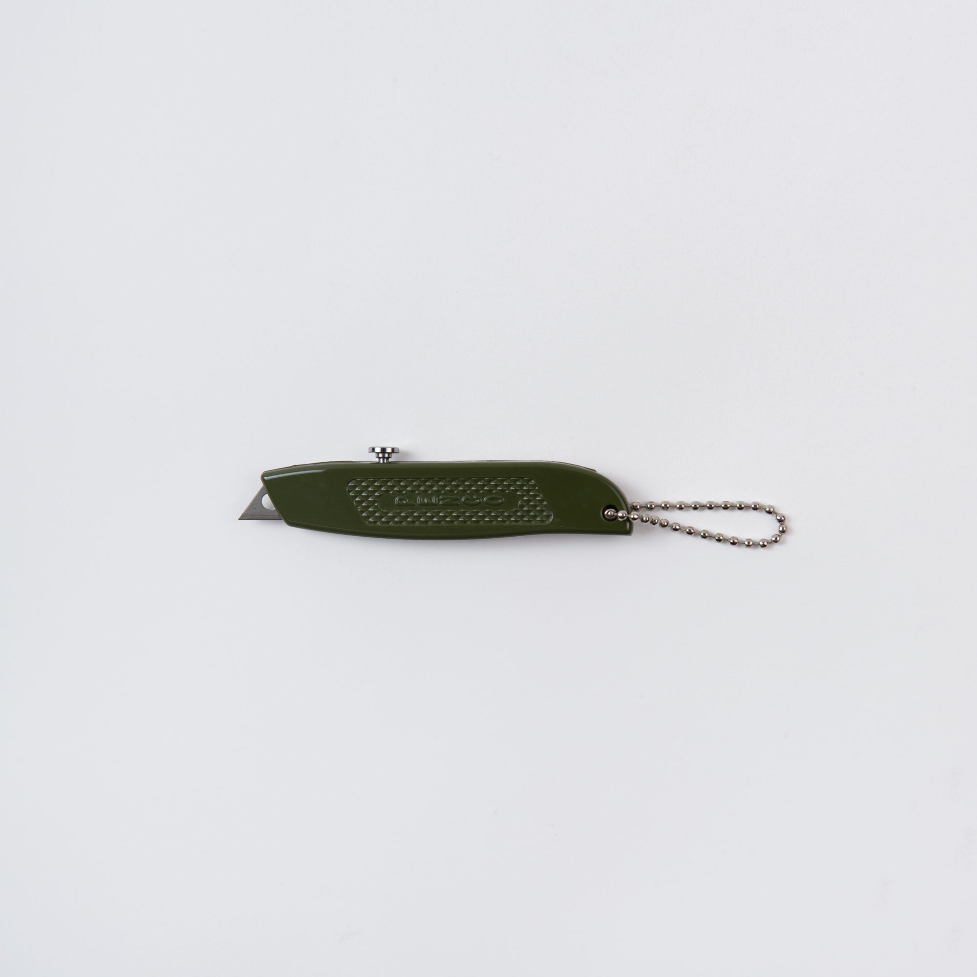 Das Penco Allzweckmesser, auch bekannt als der Cutter an der Kette, ist in Grün mit strukturiertem Griff abgebildet. Es hat eine kurze einziehbare Klinge und einen kleinen silbernen Schlüsselanhänger, der für den praktischen Gebrauch perfekt ist. Das Messer ist geschlossen auf einem schlichten weißen Hintergrund abgebildet.