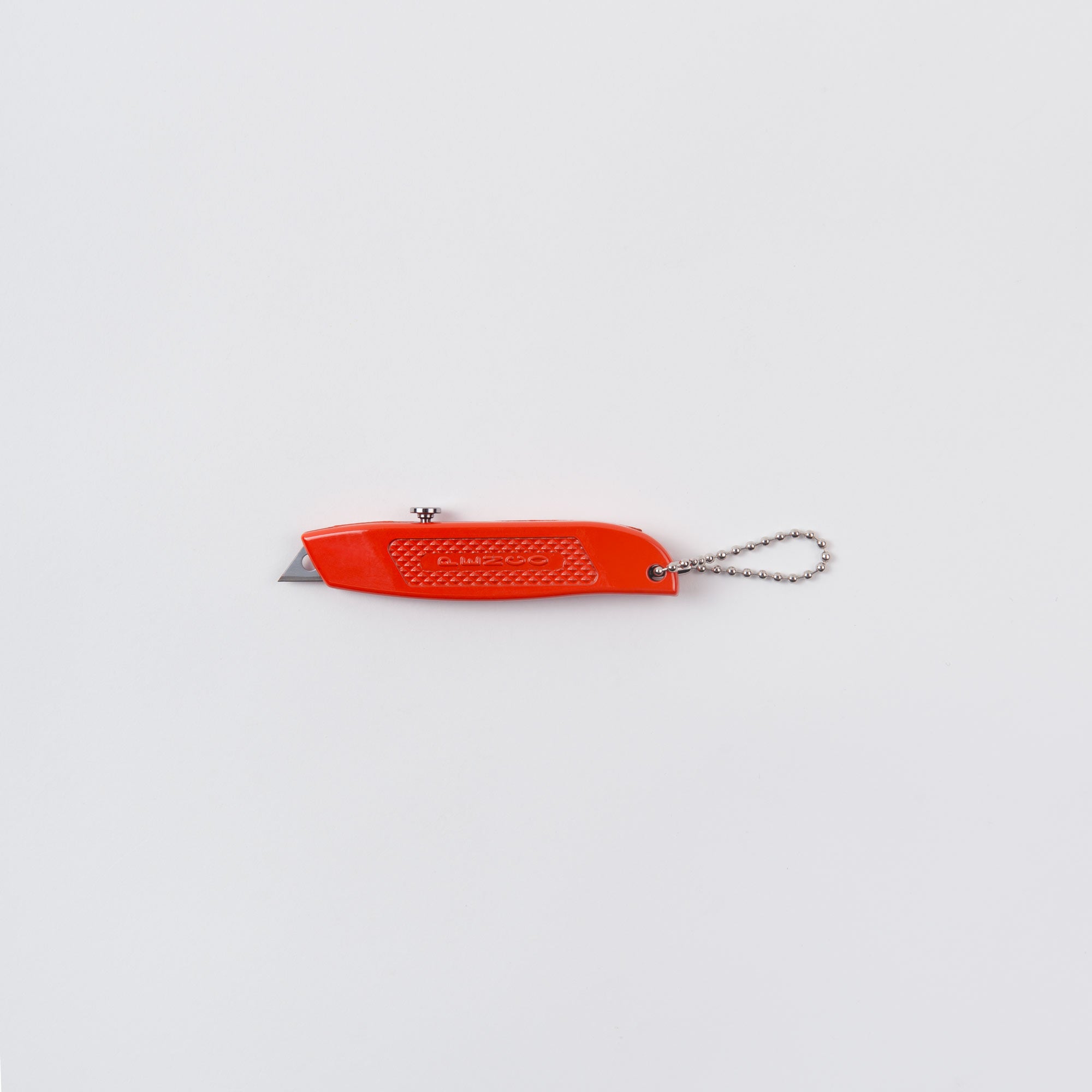 Ein rotes Penco Allzweckmesser, auch bekannt als „der Cutter an der Kette“, mit einer silbernen Kette steht auf einem weißen Hintergrund. Die Klinge ist teilweise ausgefahren und der Griff verfügt über einen strukturierten Griff für eine einfache Handhabung.