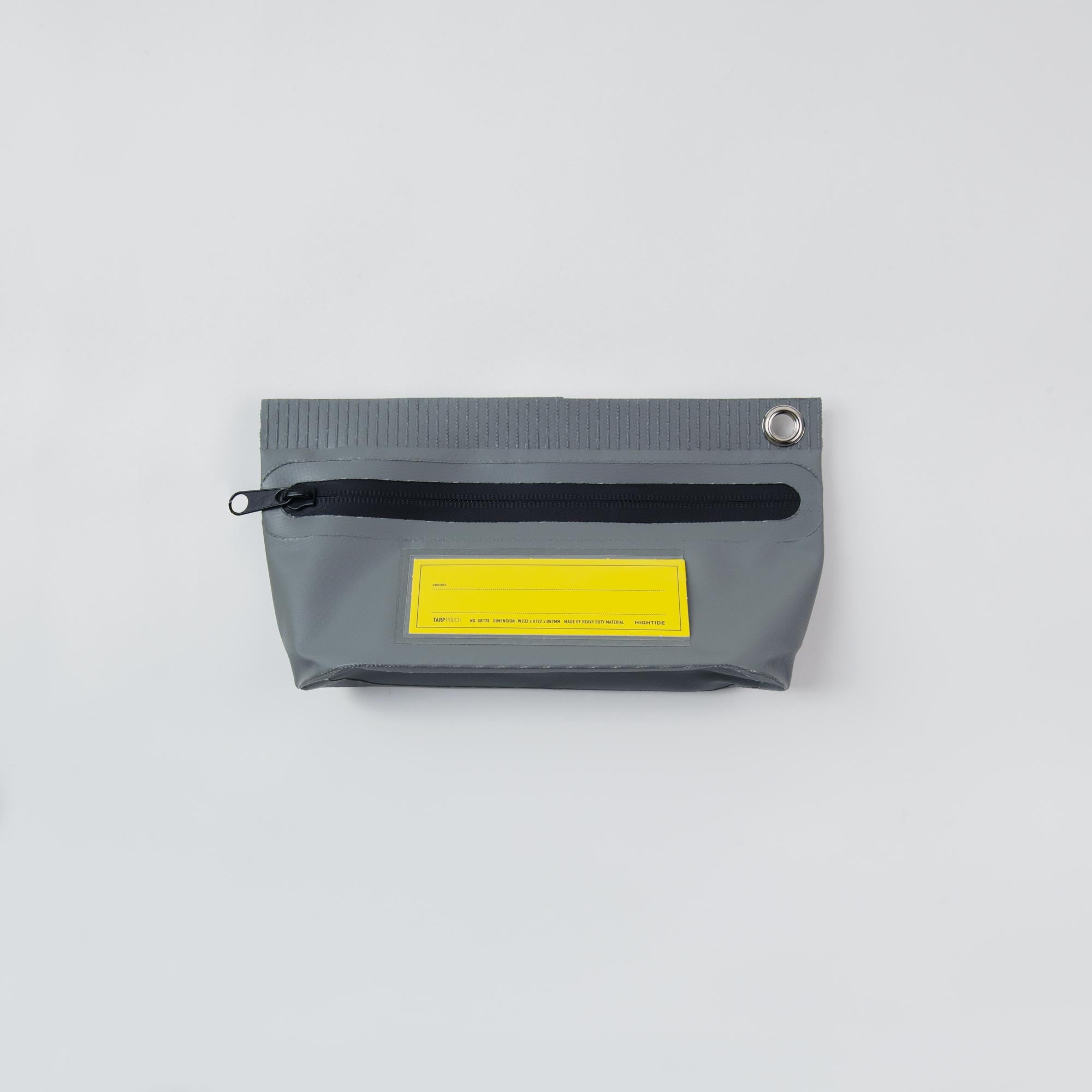 Die Tarp Pouch S von Penco ist eine graue Planenmaterialtasche mit schwarzem Reißverschluss und gelbem Frontlabel. Sie verfügt über eine Metallöse zur Befestigung eines Karabinerhakens in der oberen rechten Ecke, die auf einem schlichten weißen Hintergrund abgebildet ist.