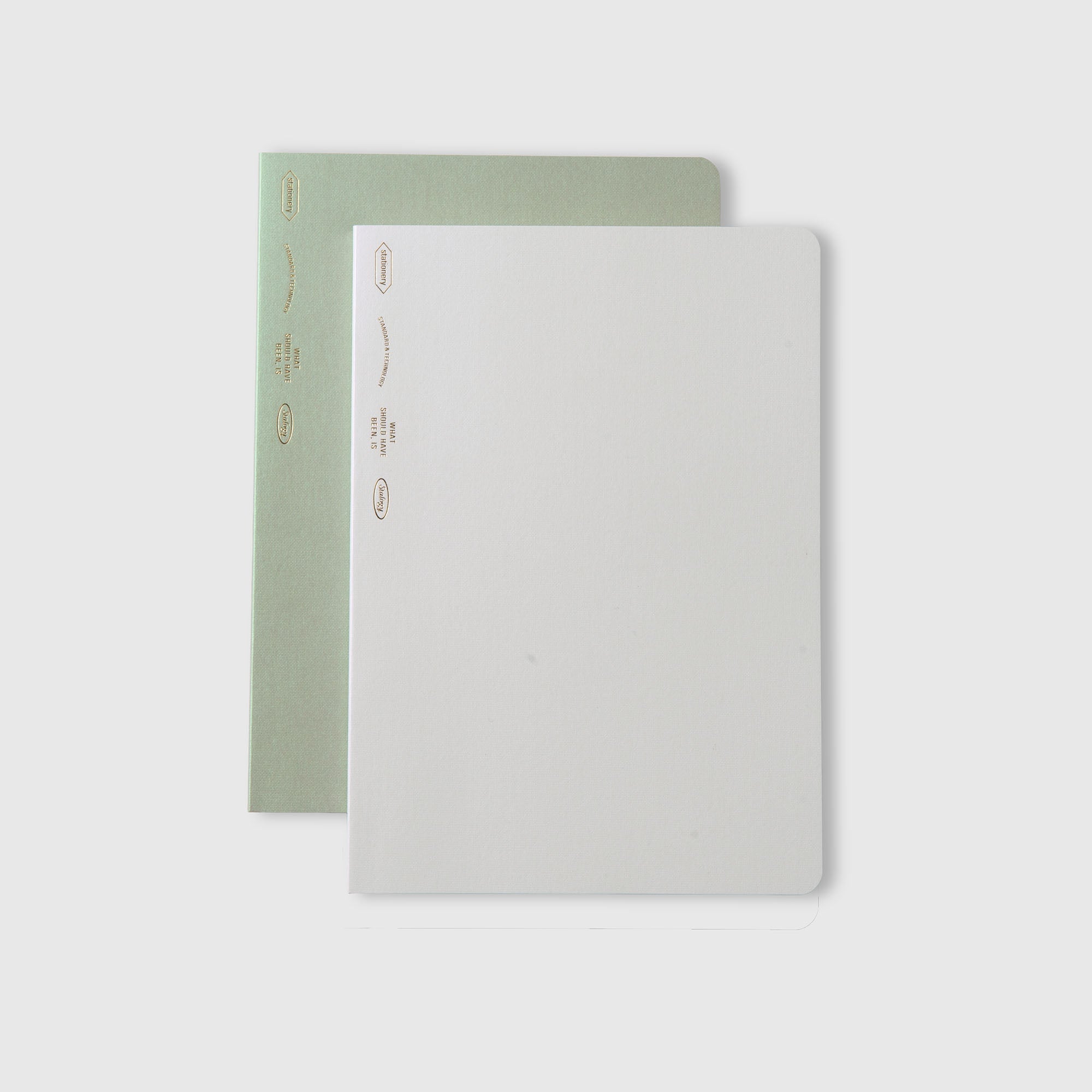 Zwei minimalistische Stalogy Editor's Series 1/2 Year Notebook A5 Limited Edition sind gestapelt: ein hellgrünes unter einem schlichten weißen, jeweils mit kleinem goldenen Text und Details am linken Rand, Teil der exklusiven 2026-Serie.