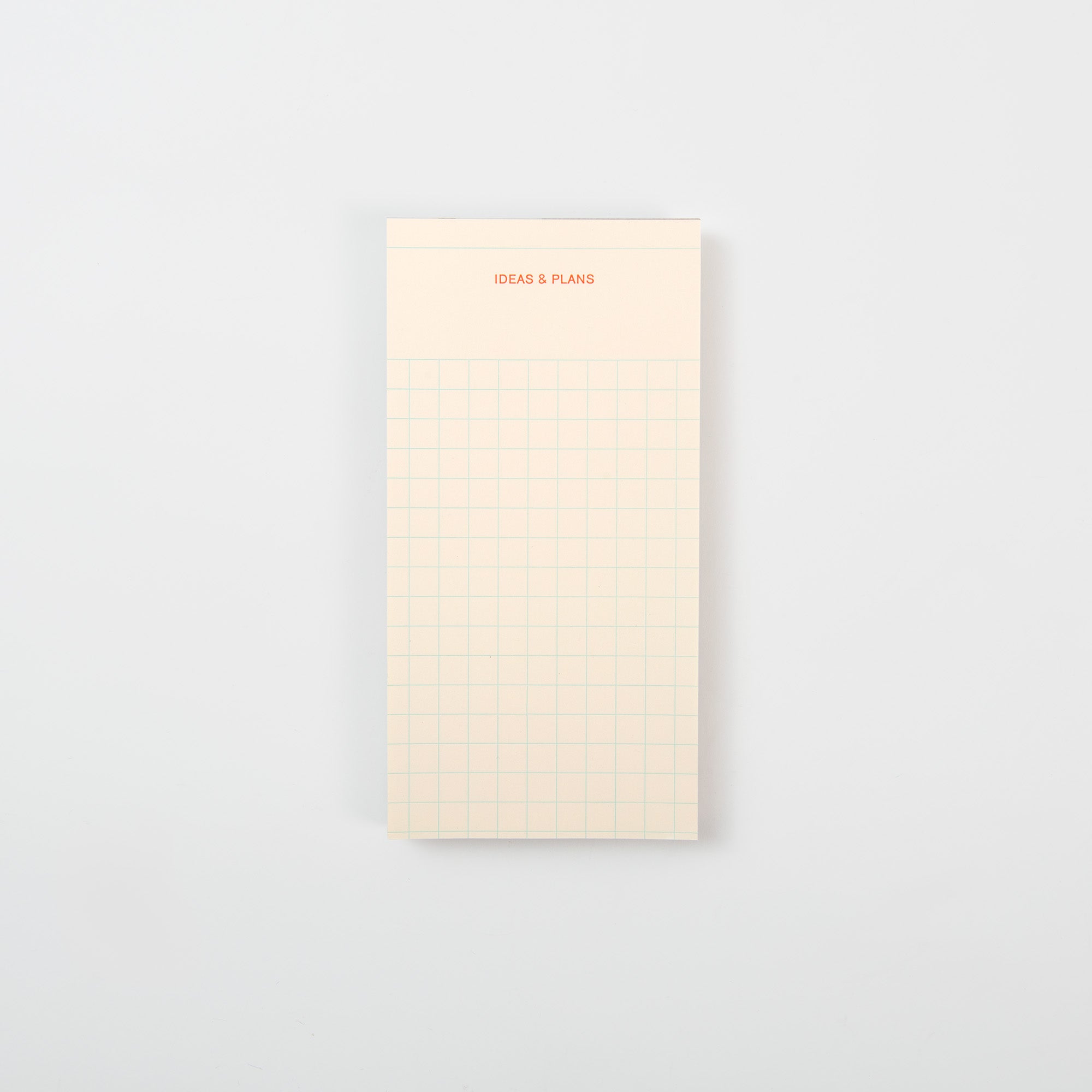 Ein cremefarbener Le Typographe "Ideen und Gedanken und Pläne" Abreißblock zeigt oben IDEAS & PLANS in Orange und darunter ein blaues Raster, dargestellt auf einem schlichten weißen Hintergrund.