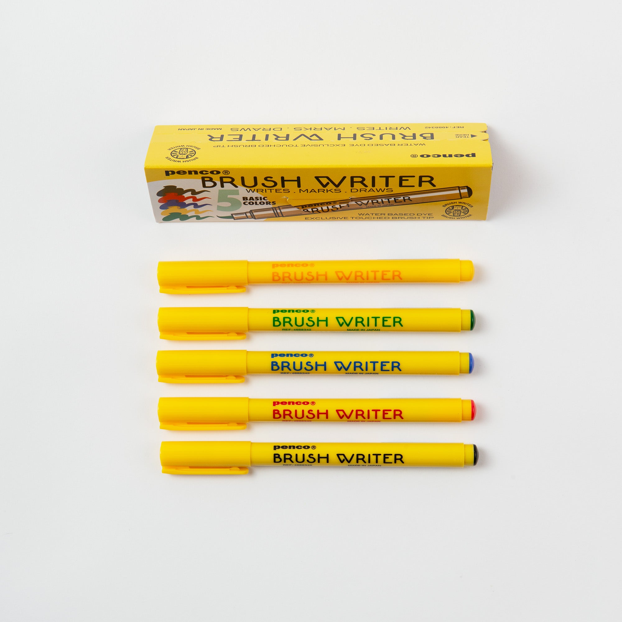 Das Penco Brushwriter-Set aus 5 Farben enthält fünf gelbe Pinselstifte mit farbigen Kappen (orange, schwarz, grün, rot, blau), die unter ihrer Verpackung aufgereiht sind. Made in Japan - ideal für Kalligrafie-Pinsel- oder Wasserfarben-Pigmente-Techniken.