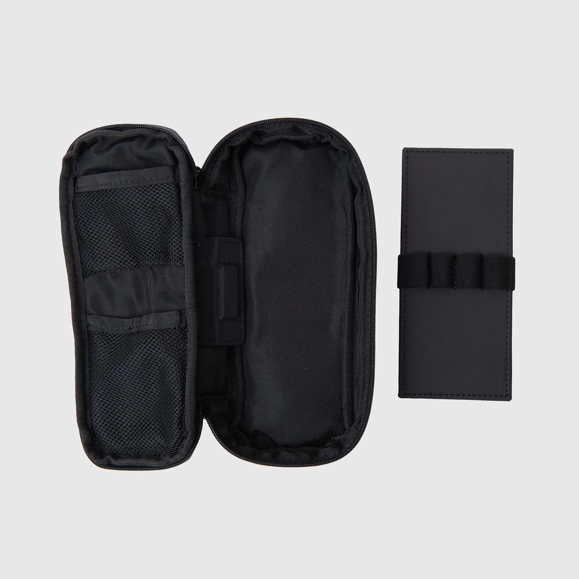Ein schwarzes, wasserabweisendes Delfonics-Stiftetui ist geöffnet und gibt den Blick auf innere Netztaschen frei, die sich perfekt zum Ordnen von Stiften und Zubehör eignen. Daneben liegt ein geschlossenes schwarzes Delfonics-Etui mit elastischen Stiftschlaufen und Magnetschleifen an der Vorderseite, die für eine sichere Aufbewahrung sorgen. Beide Etuis von Delfonics sind als wasserabweisende Stifteetuis konzipiert und werden vor einem hellgrauen Hintergrund präsentiert.