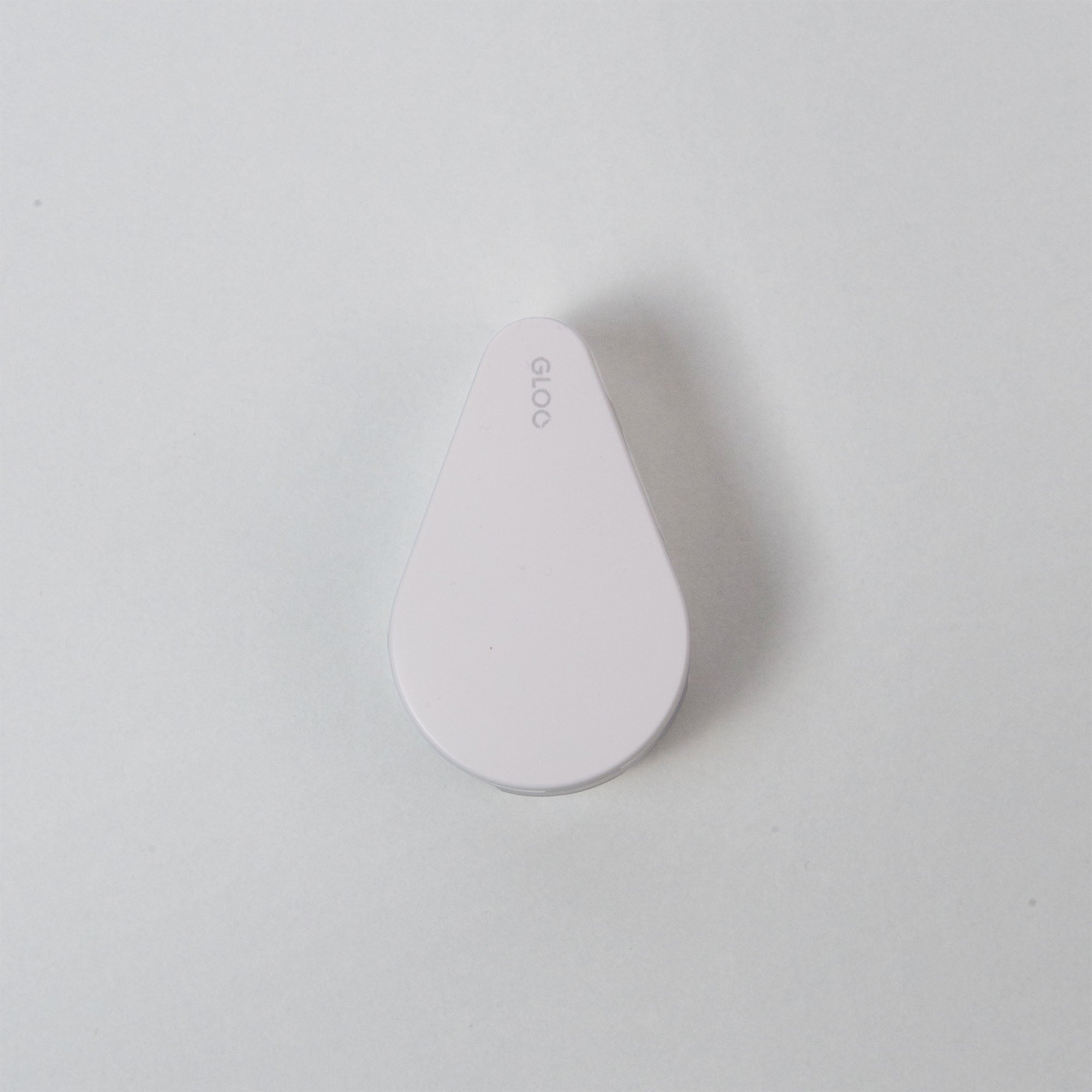 Ein schlankes, weißes, tropfenförmiges Gerät mit der eleganten Aufschrift „GLOO“ auf der Oberfläche fasziniert den Betrachter vor einem minimalistischen Hintergrund und zeigt die kuriose Form und unerklärliche Funktion des Kokuyo GLOO Tape Klebestreifen Repositionierbar.