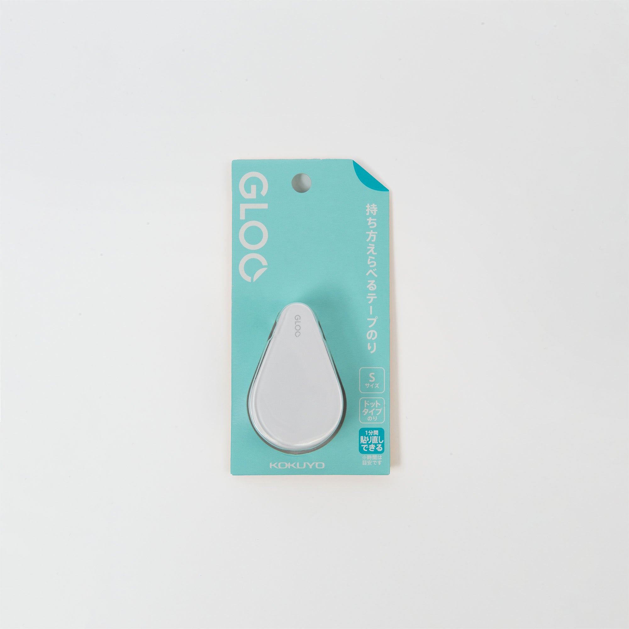 Der weiße Klebebandspender „GLOO“ von Kokuyo liegt auf einem türkisfarbenen Kartonträger mit japanischen Schriftzügen und Logos. Sein elegantes, modernes Design besticht durch eine abgerundete Form, und die Klebestreifen sind repositionierbar, bevor sie dauerhaft haften.