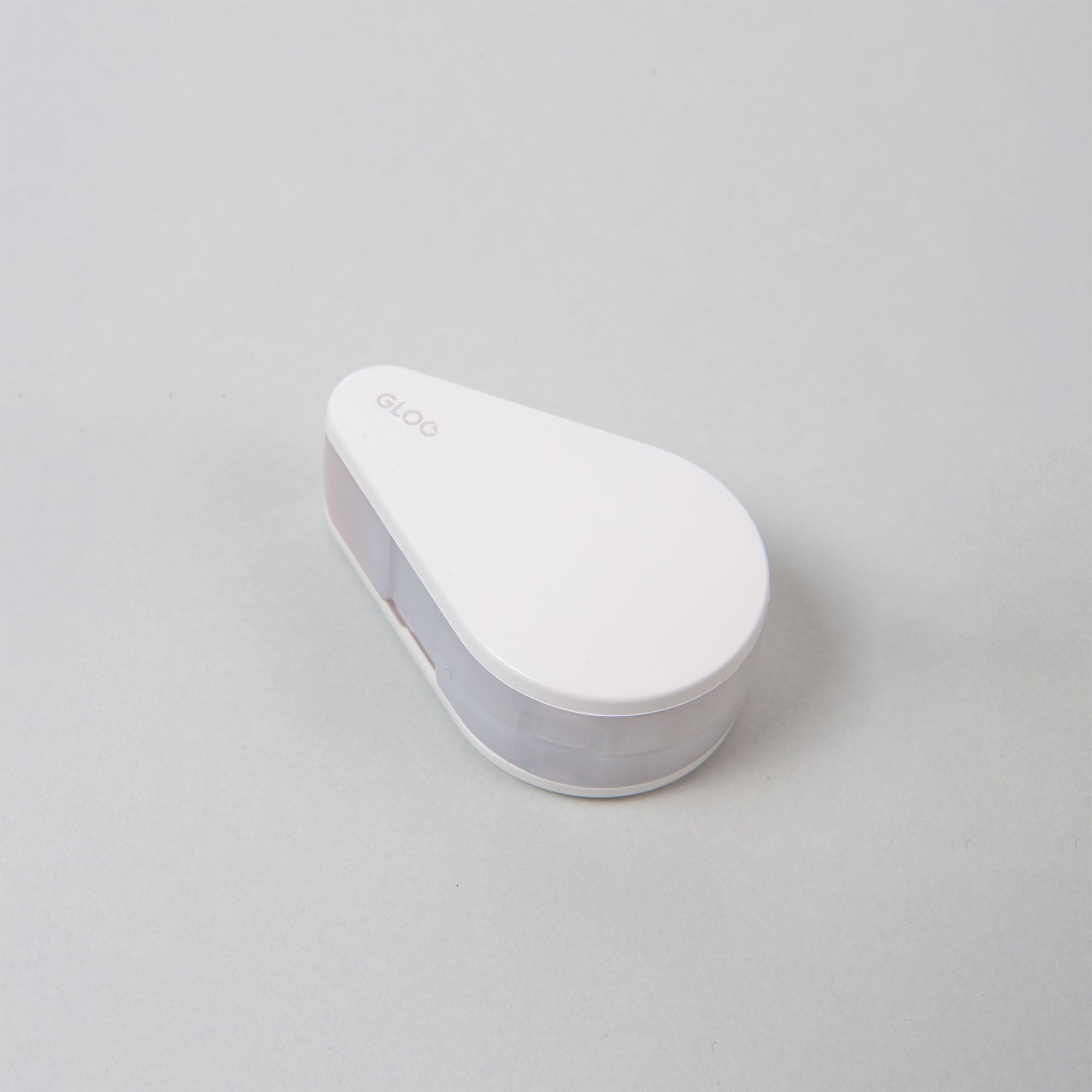 Ein weißer, tropfenförmiger Korrekturbandspender mit der Marke „Kokuyo“ zeigt elegant seine GLOO Tape Klebestreifen Repositionierbar-Funktionalität auf einer hellgrauen Oberfläche.