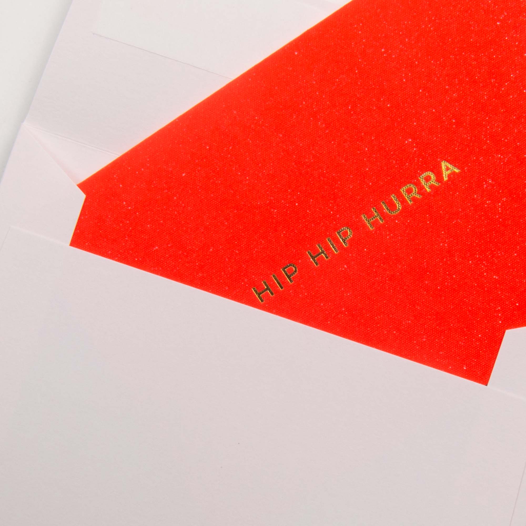 Das Gmund Kärtchen Hip Hip Hurra ist eine leuchtend rote Karte mit goldgeprägtem Schriftzug, die teilweise aus einem weißen Umschlag gezogen wird.
