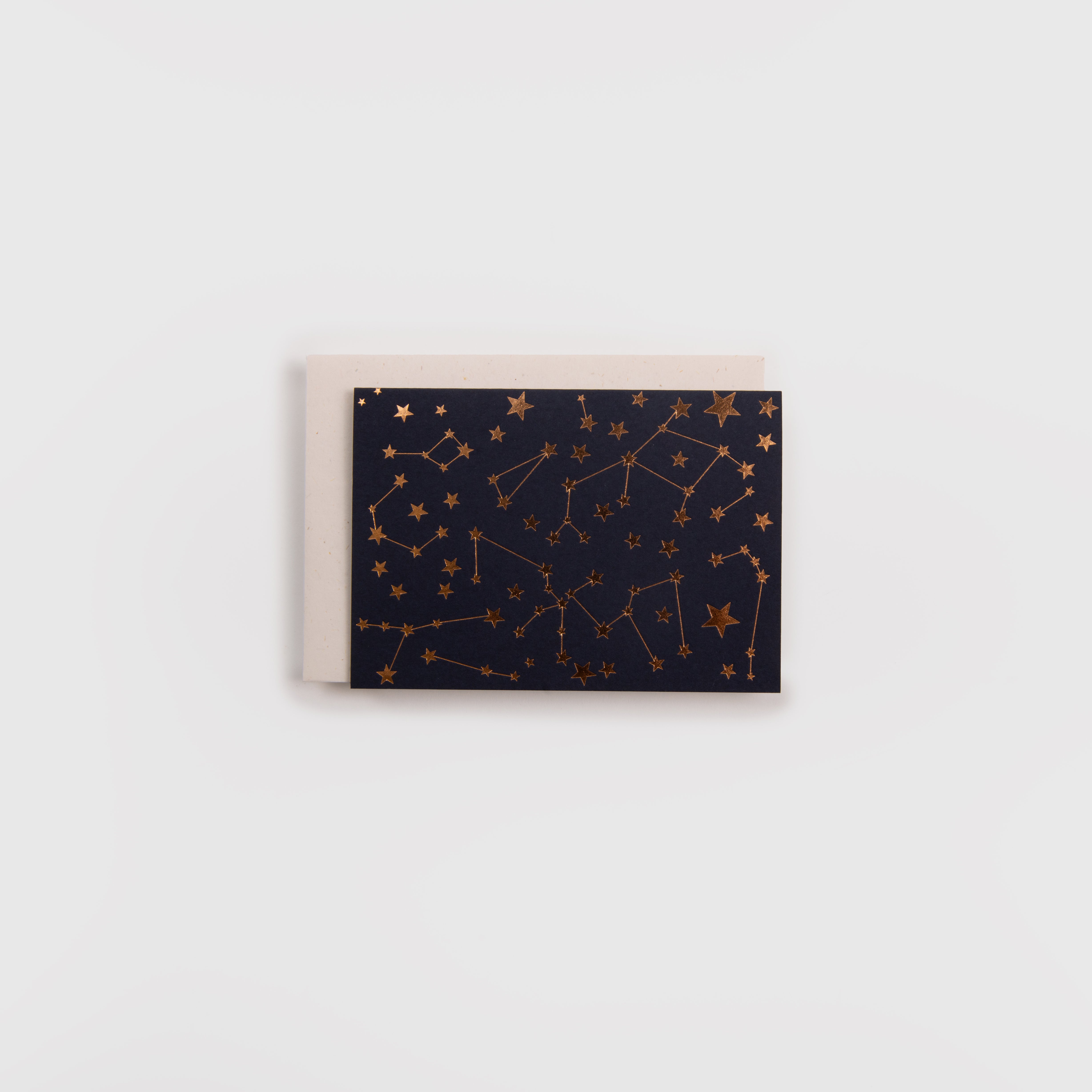Die Karte Himmelskärtchen von Gmund zeigt dunkelblaue, goldfarbene Stern- und Sternbildmotive im edlen Buchdruck, gepaart mit einem einfarbig beigen Umschlag aus hochwertigem Gmund-Papier, beides vor einem weißen Hintergrund.