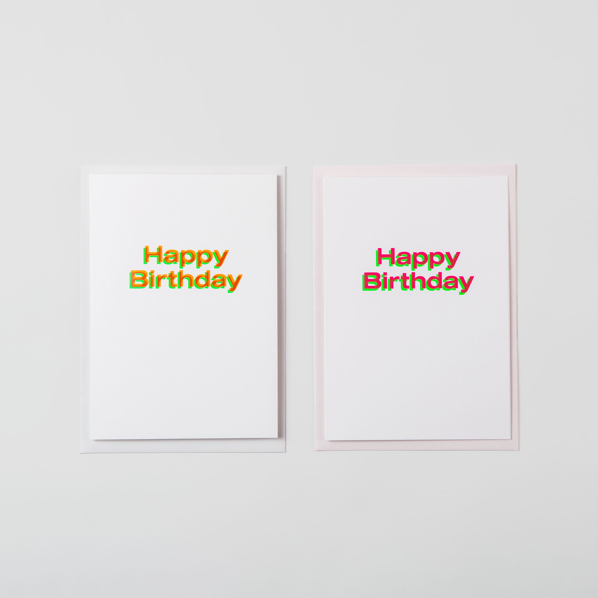 Zwei Happy Birthday-Karten im A5-Format von paperlux.store zeigen einen farbenfrohen, mehrschichtigen „Happy Birthday“-Text auf weißem Hintergrund mit minimalistischem Design. Sie wurden in Hamburg mit höchster Präzision gefertigt und passen perfekt nebeneinander auf eine helle Oberfläche.