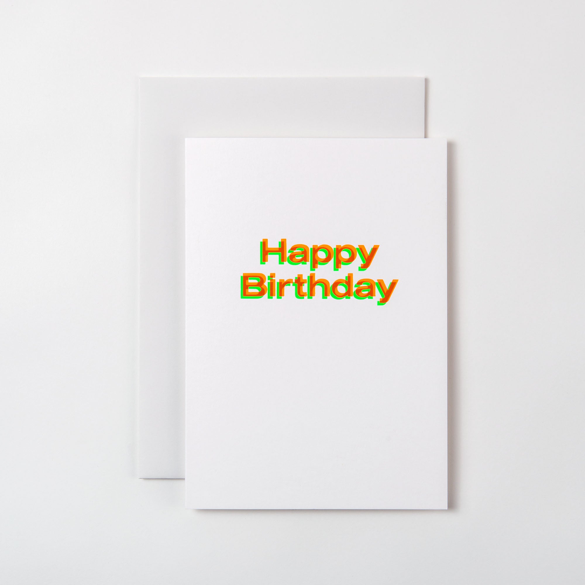 Die weiße „Happy Birthday Karte A5“ von paperlux.store, gestaltet in Hamburg, zeigt einen bunten, mehrschichtigen Text in Heißfolienprägung. Er ruht auf einer Blankokarte auf einem hellgrauen Untergrund.