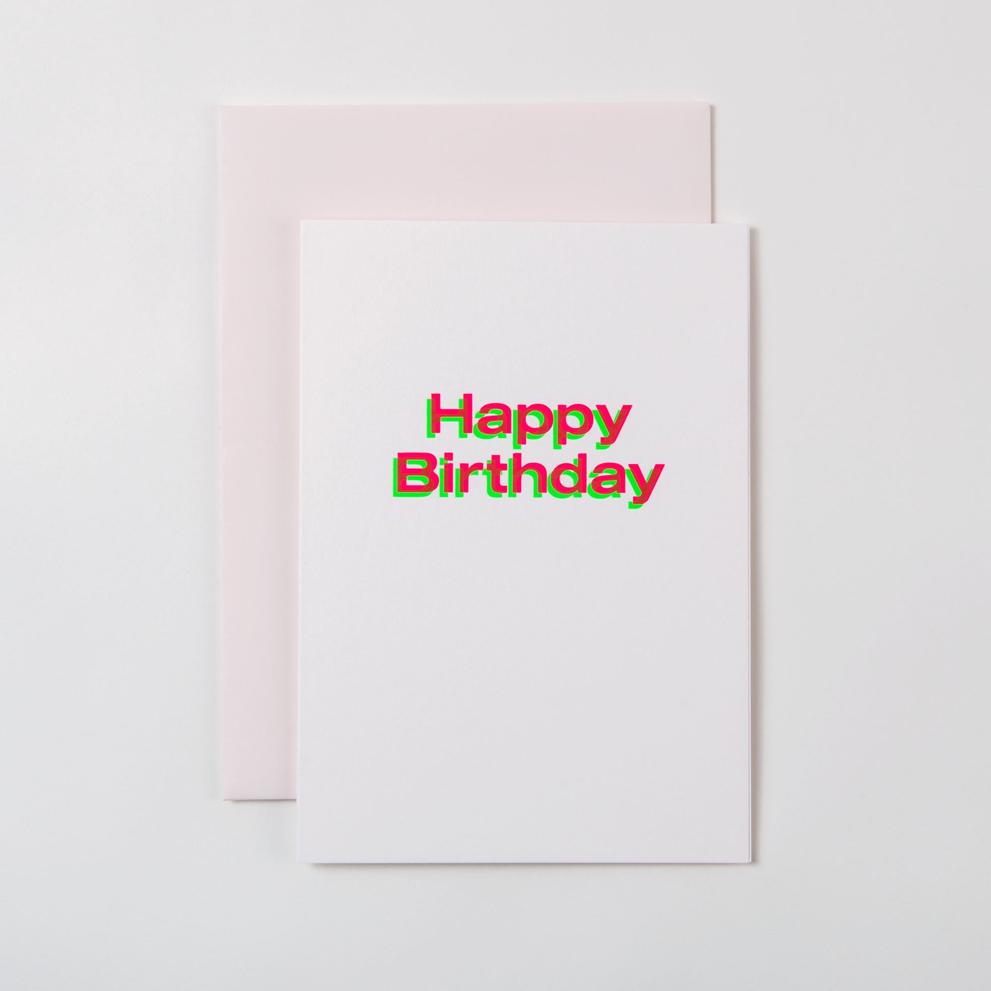 Eine weiße A5-Karte „Happy Birthday“ von paperlux.store mit kräftigem, farbenfrohem Text und exquisiter Heißfolienprägung, auf einem hellrosa Umschlag. Ideal für Liebhaber schön gestalteter Geburtstagskarten.
