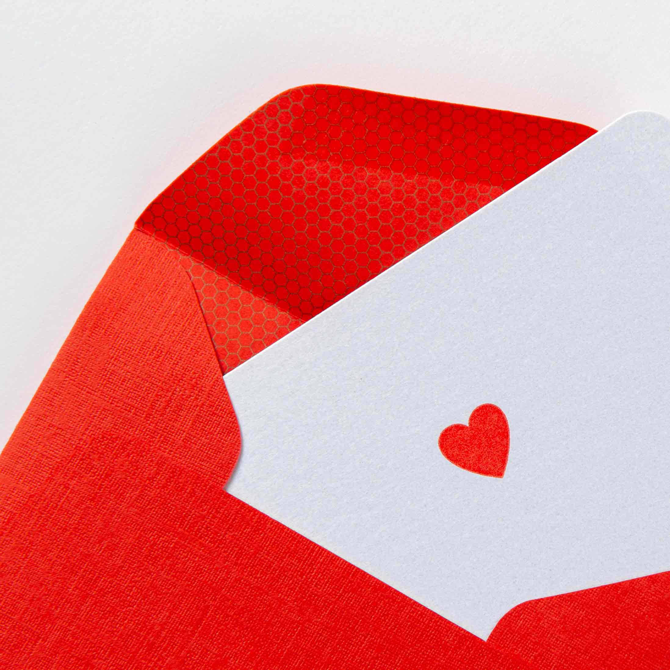 Die Herz - Minikarte von Le Typographe ist eine Buchdruckkarte mit einem roten Herzen, das teilweise in einen roten Umschlag mit einer dezent strukturierten Innenseite gesteckt ist und Liebe und Zuneigung hervorruft.