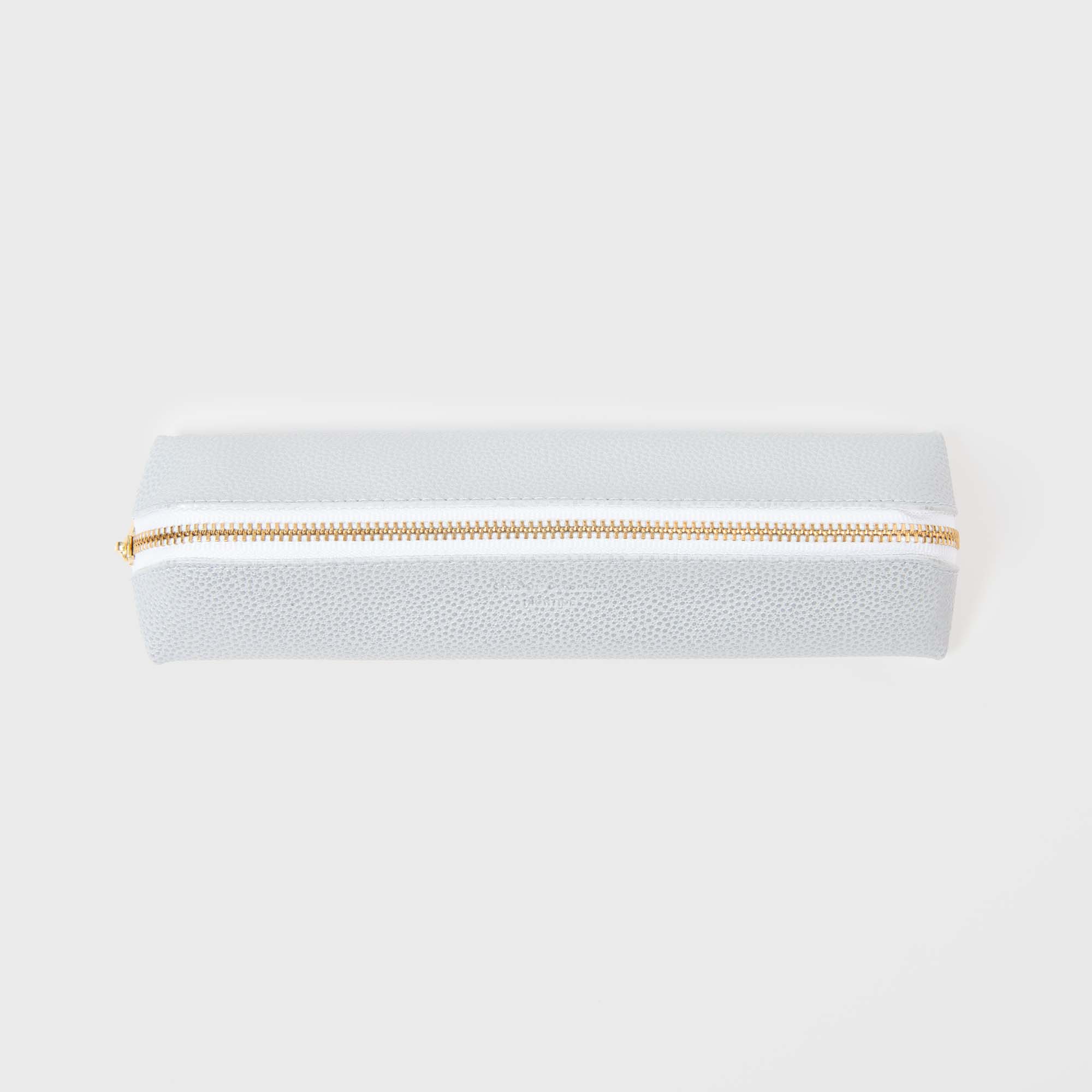 Das Hightide Fastener Pen Case ist in Hellgrau mit strukturierter Oberfläche auf weißem Hintergrund erhältlich und verfügt über einen kupferfarbenen Reißverschluss an der Oberseite, der das minimalistische Design elegant ergänzt.
