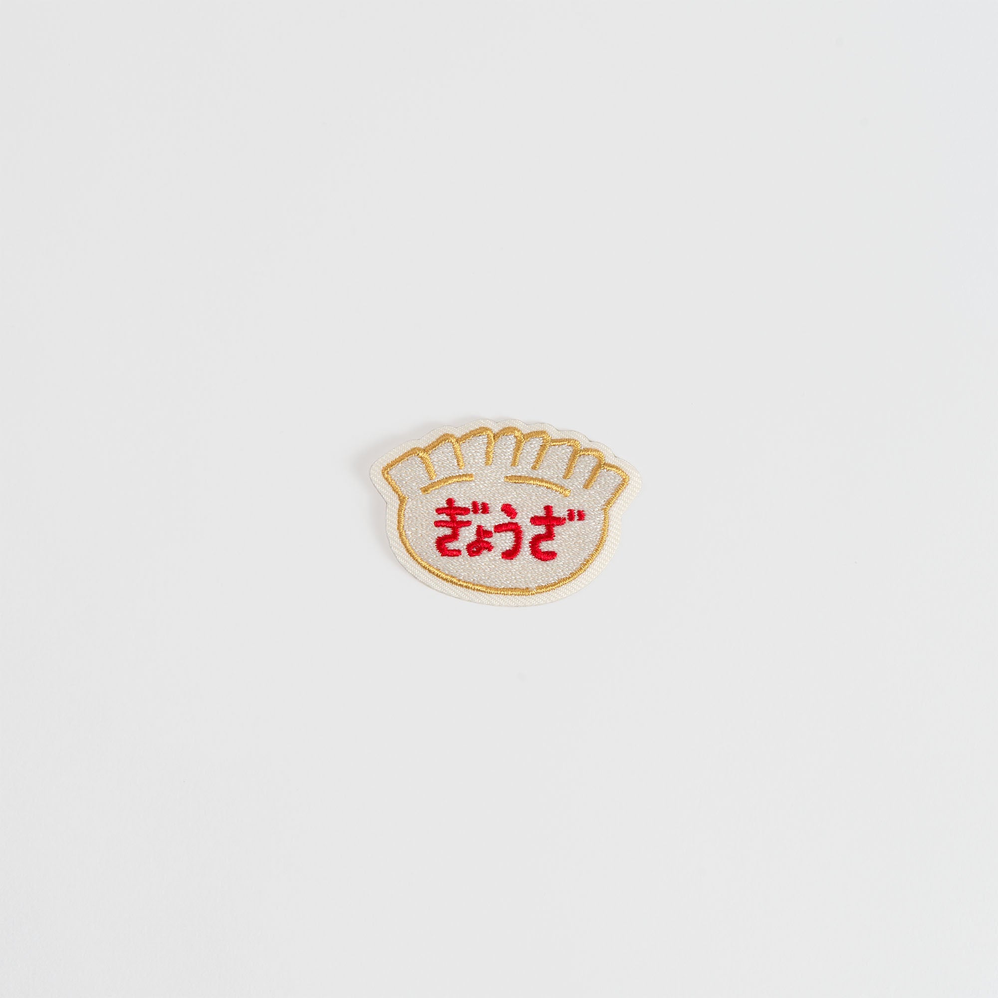 Der Hightide New Retro Patch Sticker von Hightide ist ein kleiner gestickter Gyoza-Knödel mit roten japanischen Schriftzeichen, der den Charme der Showa-Ära einfängt und auf einem schlichten weißen Hintergrund abgebildet ist.