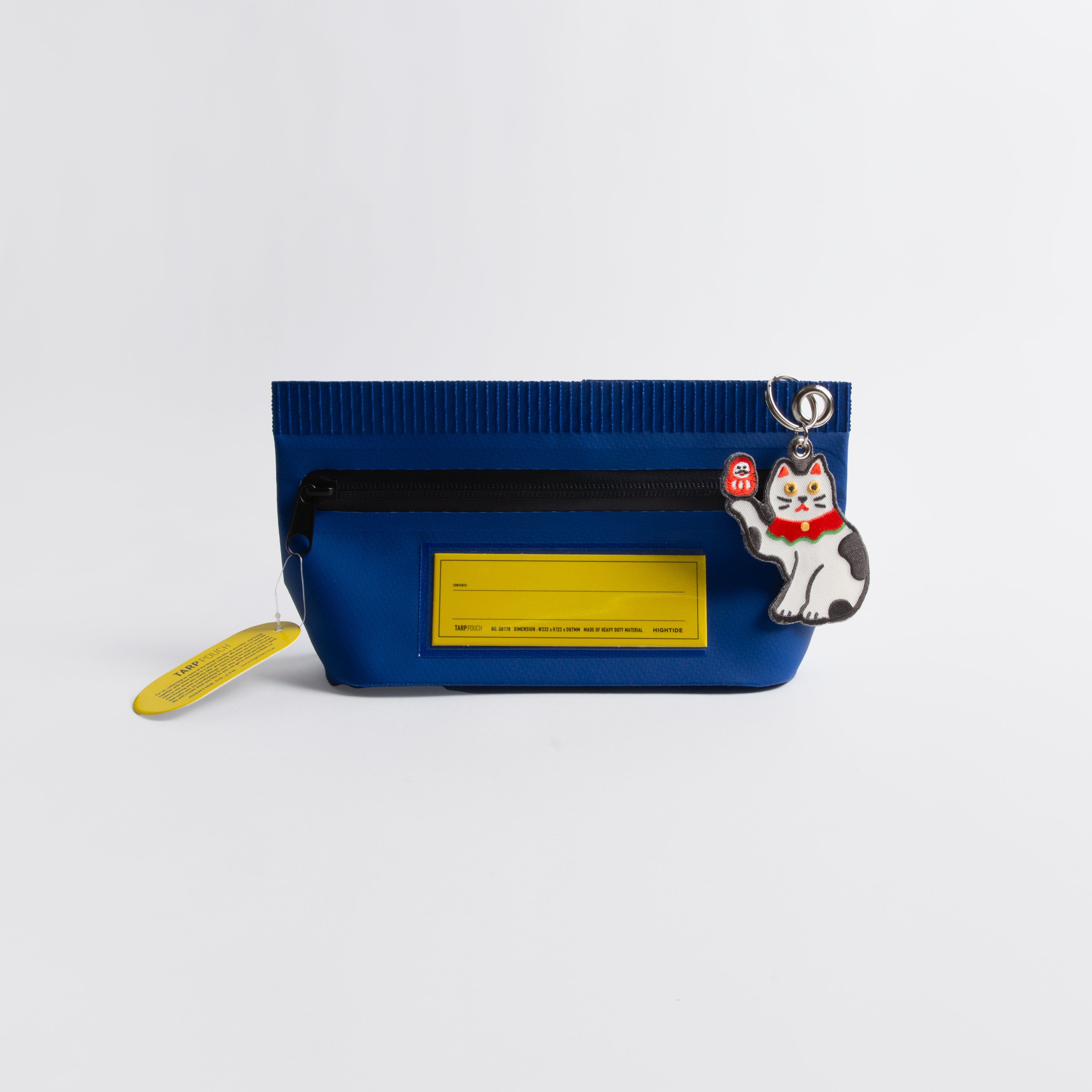 Der Hightide Stitch Work Keychain - Kamera, Daruma & Glückskatze ist ein blauer Reißverschlussbeutel mit einem gelben Anhänger, schwarzem Reißverschluss und einem Schlüsselanhänger mit einer weiß-schwarzen Katze mit rotem Halsband und einem kleinen roten Anhänger. Inspiriert von japanischen Geschenkideen.