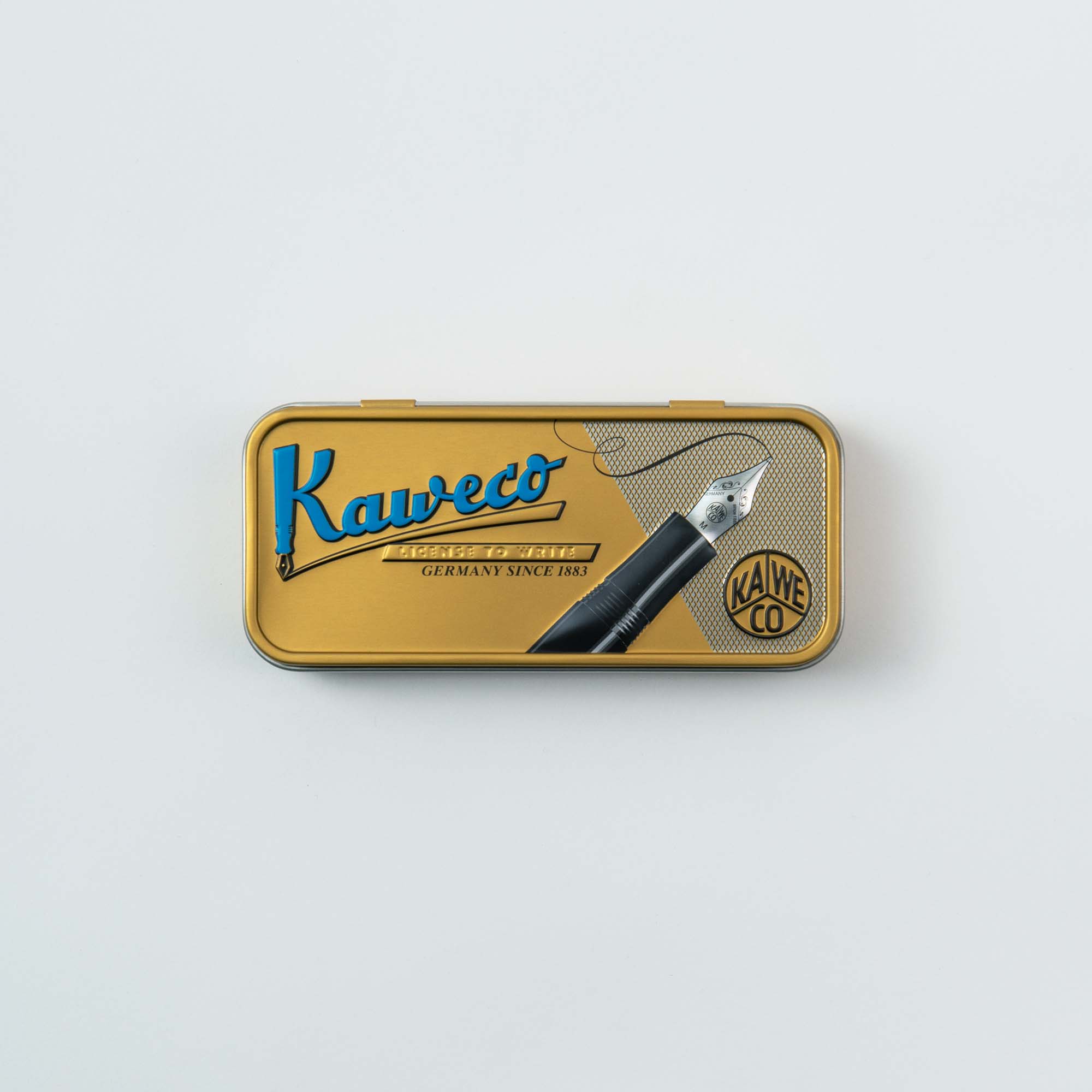 Die goldene Blechdose im Vintage-Design mit blauem Kaweco-Schriftzug und klassischer Stiftgrafik. Das runde Logo „Germany since 1883“ spiegelt zeitlose Eleganz in kompakter Perfektion wider. Produkt: Füllhalter M – Aluminium von Kaweco.