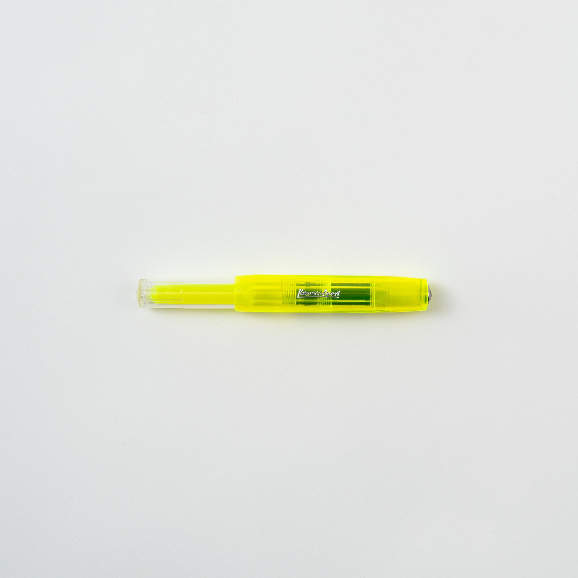 Ein gelbes Kaweco Textmarker-Set Neongelb mit transparenter Kappe liegt auf einer schlichten weißen Oberfläche und ist bereit zum Lernen und Lesen.