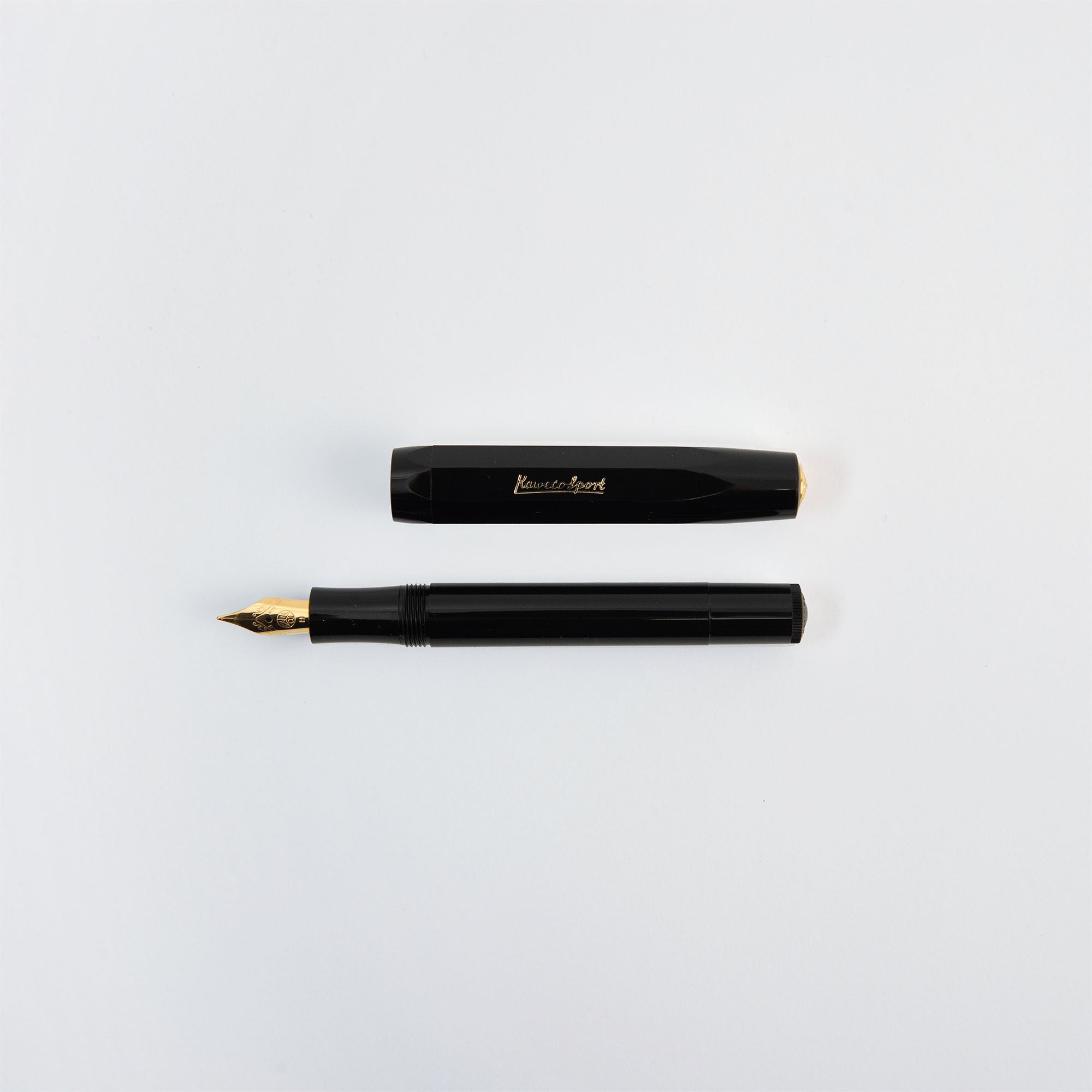 Ein schwarzer Kaweco Classic Sport - Füllhalter von Kaweco mit Goldfeder liegt auf einer weißen Fläche, die Kappe ist knapp über dem Stift angebracht.