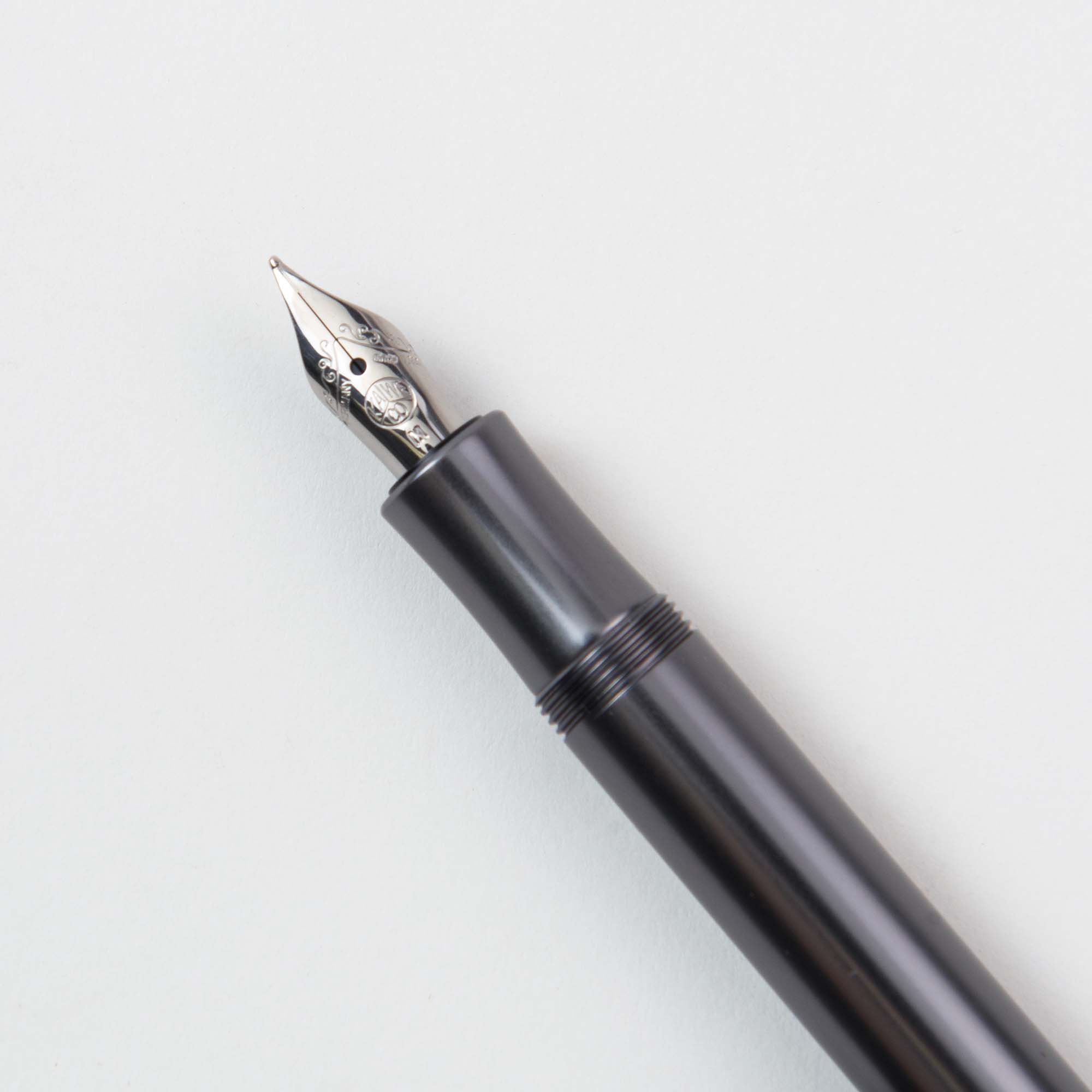Der Kaweco Füllhalter M – Aluminium verfügt über einen schlanken schwarzen Schaft und eine glänzende Silberfeder, die sich elegant von einem schlichten weißen Hintergrund abhebt und mit der Raffinesse eines klassischen Kugelschreibers konkurriert.