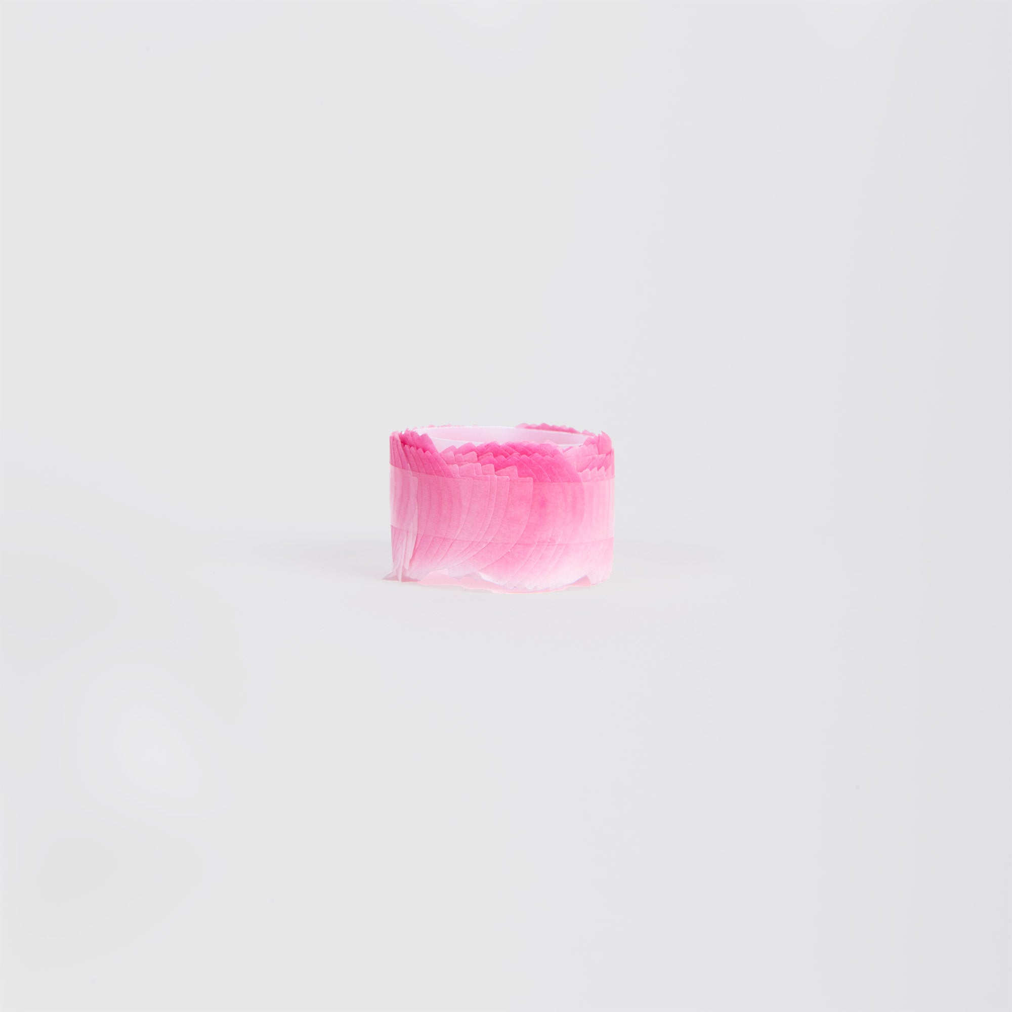 Eine kompakte Rolle Washi-Tape „Kirschblüte“ von Paper Poetry mit gewellten rosa Rändern ist auf einem schlichten weißen Hintergrund platziert, wodurch die zarte Textur und die leuchtende Farbe betont werden.