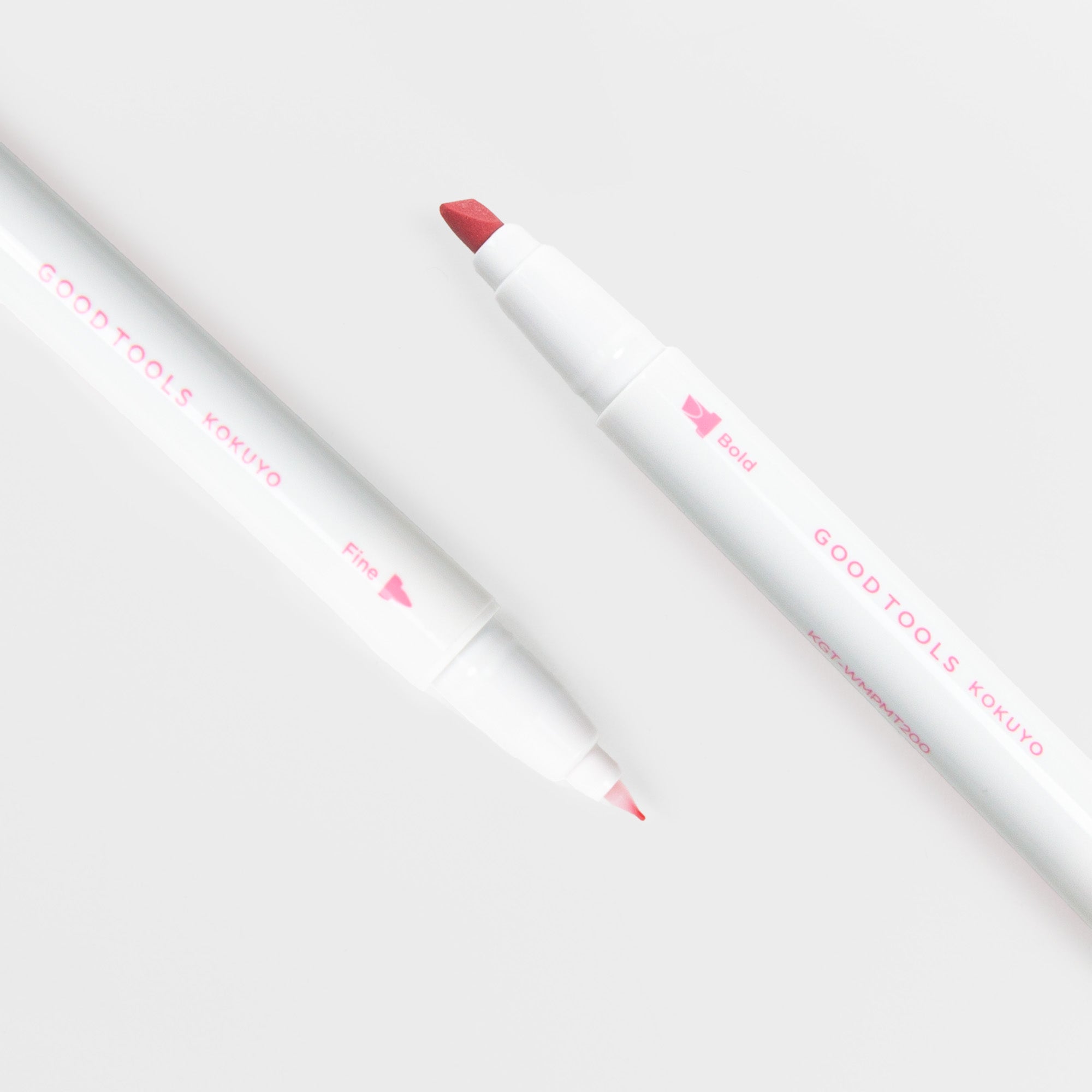 Zwei Kokuyo Two-Way Marking Pens mit feinen und kräftigen rosa Spitzen liegen diagonal auf einer weißen Fläche. Beide sind mit dem rosafarbenen Schriftzug "GOODTOOLS KOKUYO" und den Spitzengrößen versehen - ideal als Filzstift-Marker für Journaling.