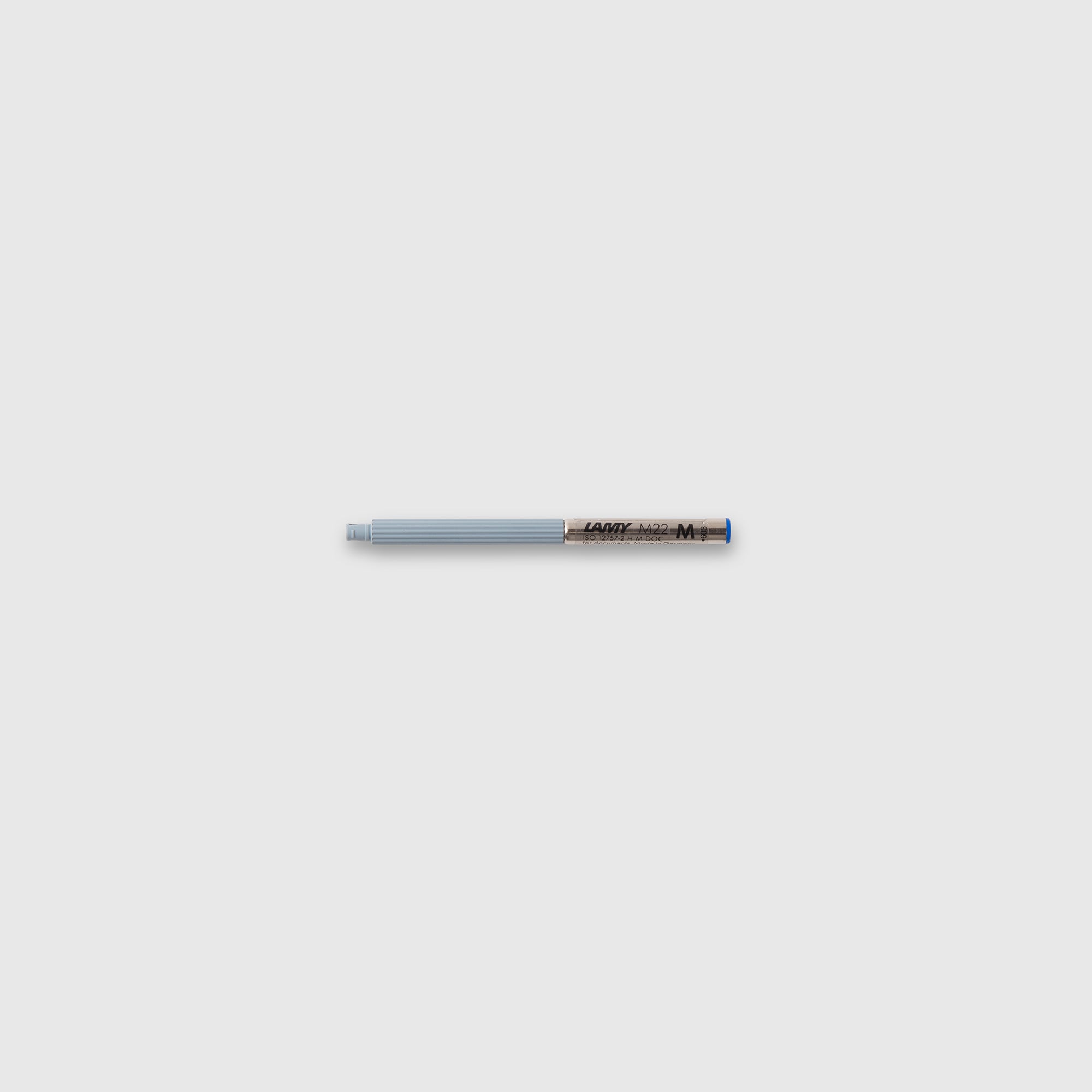 Eine LAMY Compactmine M22 Mine von Lamy mit blauer Kappe, grauem Korpus und schwarzer Schrift liegt waagerecht auf einem schlichten hellgrauen Hintergrund.