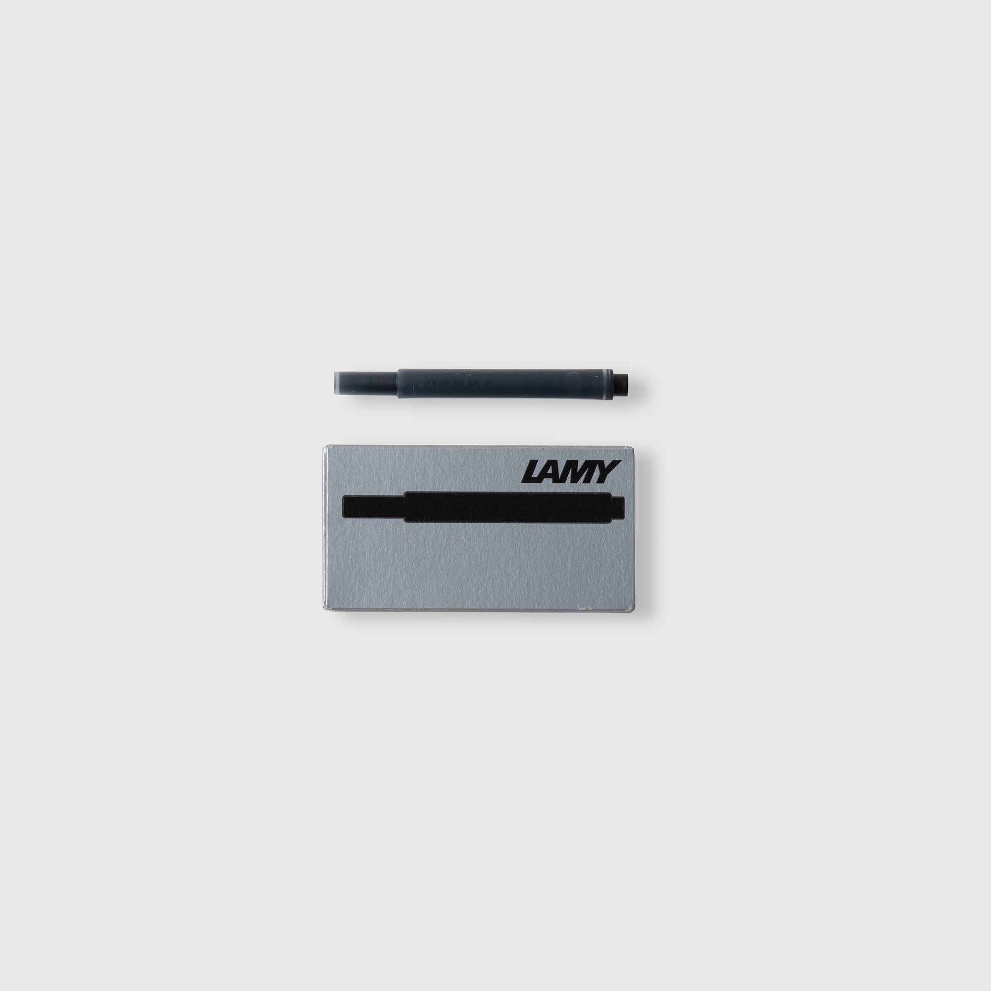 Eine schwarze LAMY T10 Tintenpatrone ist über einer grauen Lamy Schachtel mit Logo und Patronenabbildung abgebildet, die für den LAMY safari Füllhalter entworfen wurde - perfekt für Ihren Schreibbedarf, alles vor einem weißen Hintergrund.