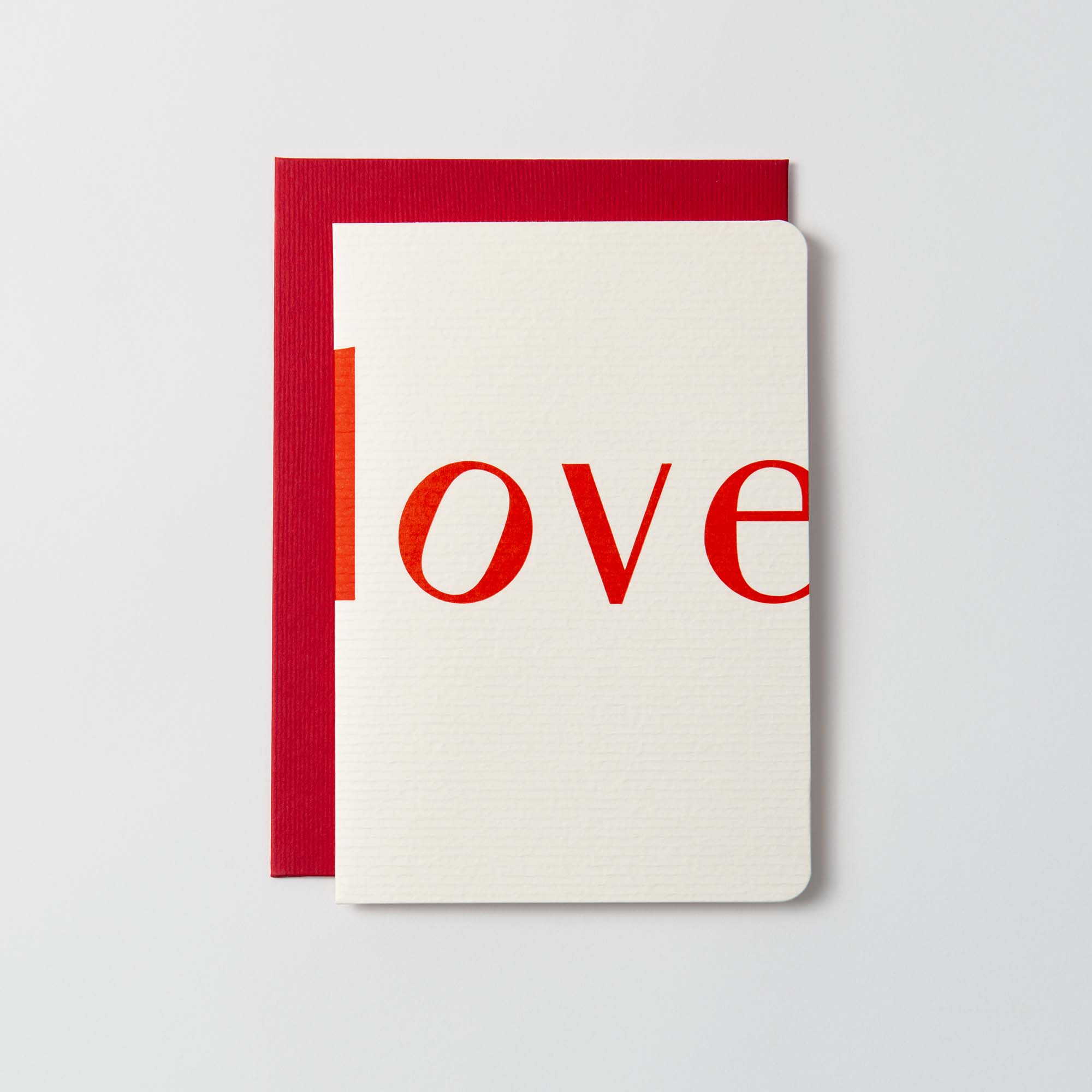 Die L O V E Karte und Kuvert von Le Typographe zeigt das Wort „Love“ in kräftigen roten Kleinbuchstaben auf einem weißen Umschlag, der teilweise die rote Karte freigibt. Das elegante, zeitlose Design ruht auf einer schlichten weißen Oberfläche.