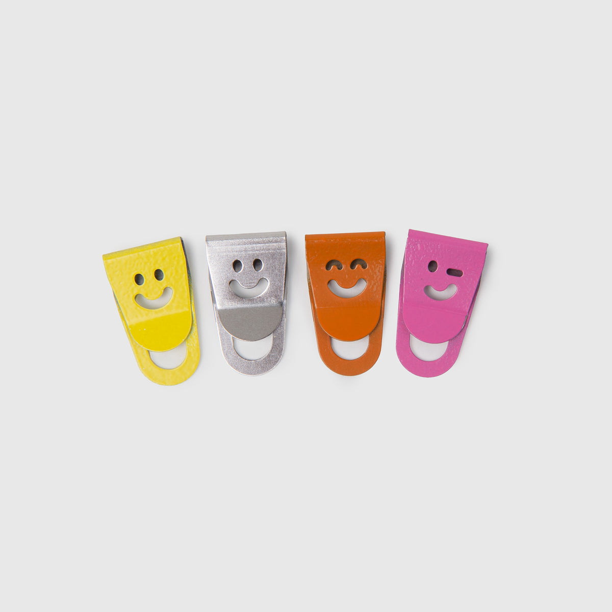 Le Typographe Mini-Clips Smiley in Gelb, Silber, Orange und Rosa, jeweils mit einem ausgestanzten Smiley-Motiv zur Organisation auf dem Schreibtisch.