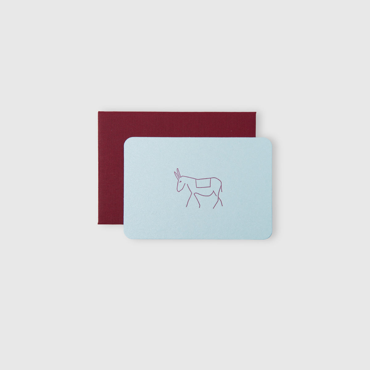Eine hellblaue Le Typographe Mini-Karte „Esel“ mit einer schlichten, weinroten Strichzeichnung eines Esels wird auf einem schlichten weißen Hintergrund mit einem weinroten Umschlag kombiniert. Diese bezaubernde Karte besticht durch den traditionellen Buchdruck, der ihr eine elegante, haptisch ansprechende Optik verleiht.