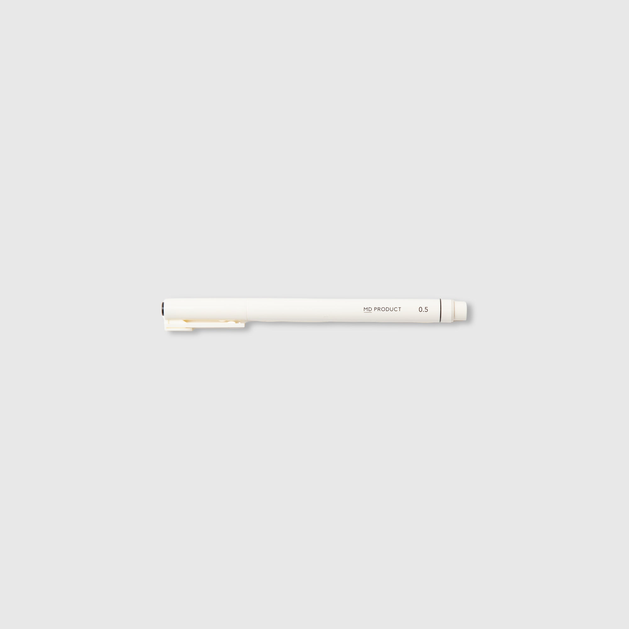 Ein weißer Midori MD Drawing Pen 0,5 mm mit Clip liegt waagerecht auf einem hellgrauen Hintergrund. Dieser minimalistische Stift von Midori ist am hinteren Ende mit einem schlichten Schriftzug versehen und verwendet wasserbasierte Pigmenttinte, die für glatte und präzise Linien sorgt.