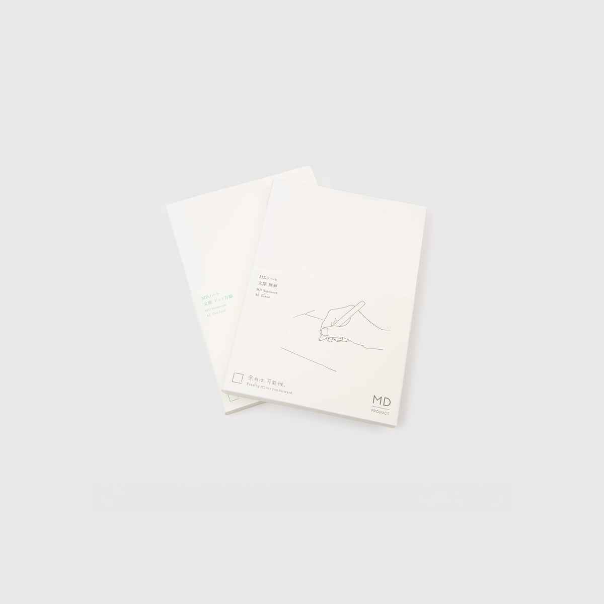 Zwei minimalistische weiße Notizbücher, von denen sich eines teilweise mit dem anderen überlappt, jeweils mit einer schlichten Strichzeichnung einer schreibenden Hand und japanischem Text auf dem Einband. Beide „Midori MD Notebook A6“ von Midori zeichnen sich durch ein klares, modernes Design vor hellgrauem Hintergrund aus und sind fadengebunden, was für Langlebigkeit und eine elegante Optik sorgt.