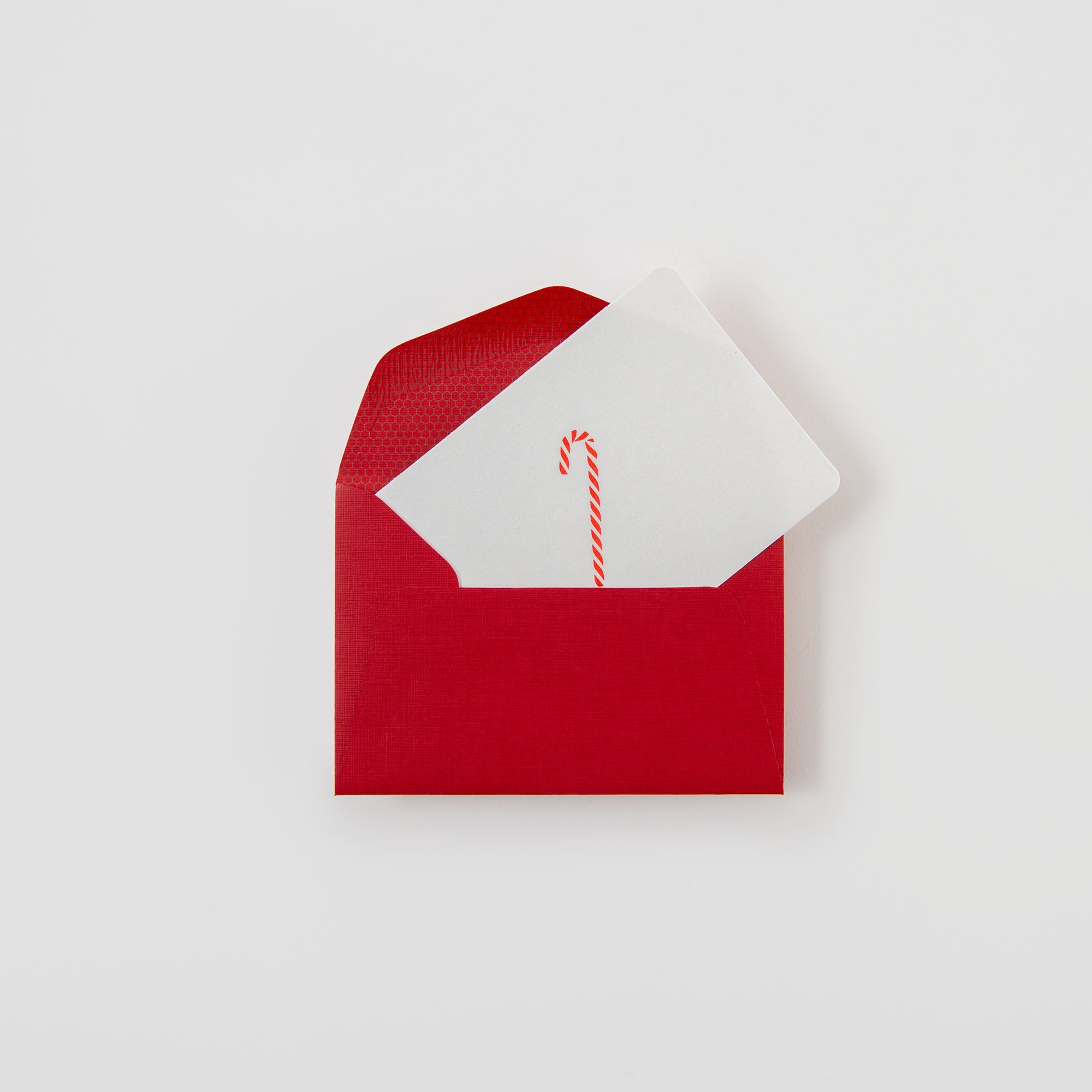 Die Zuckerstange - Mini Karte von Le Typographe ist teilweise in einem roten Umschlag abgebildet. Die Karte zeigt eine kleine rot-weiße Zuckerstange-Illustration vor einem schlichten weißen Hintergrund.