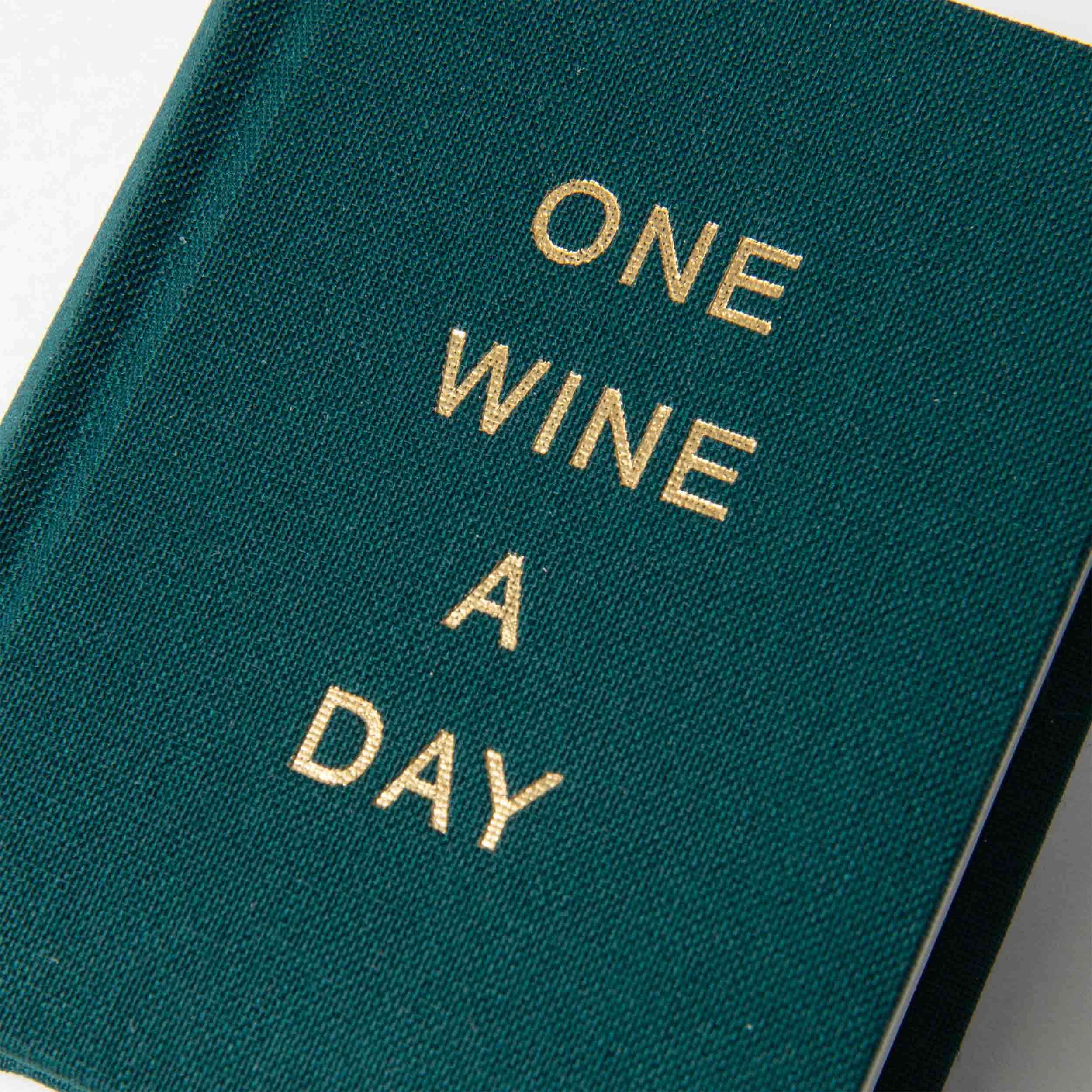 Ein flaschengrüner-Cover von paperlux.store zeigt die elegante Goldprägung „ONE WINE A DAY“ und erinnert so an das Weinjournal eines Top-Sommeliers.