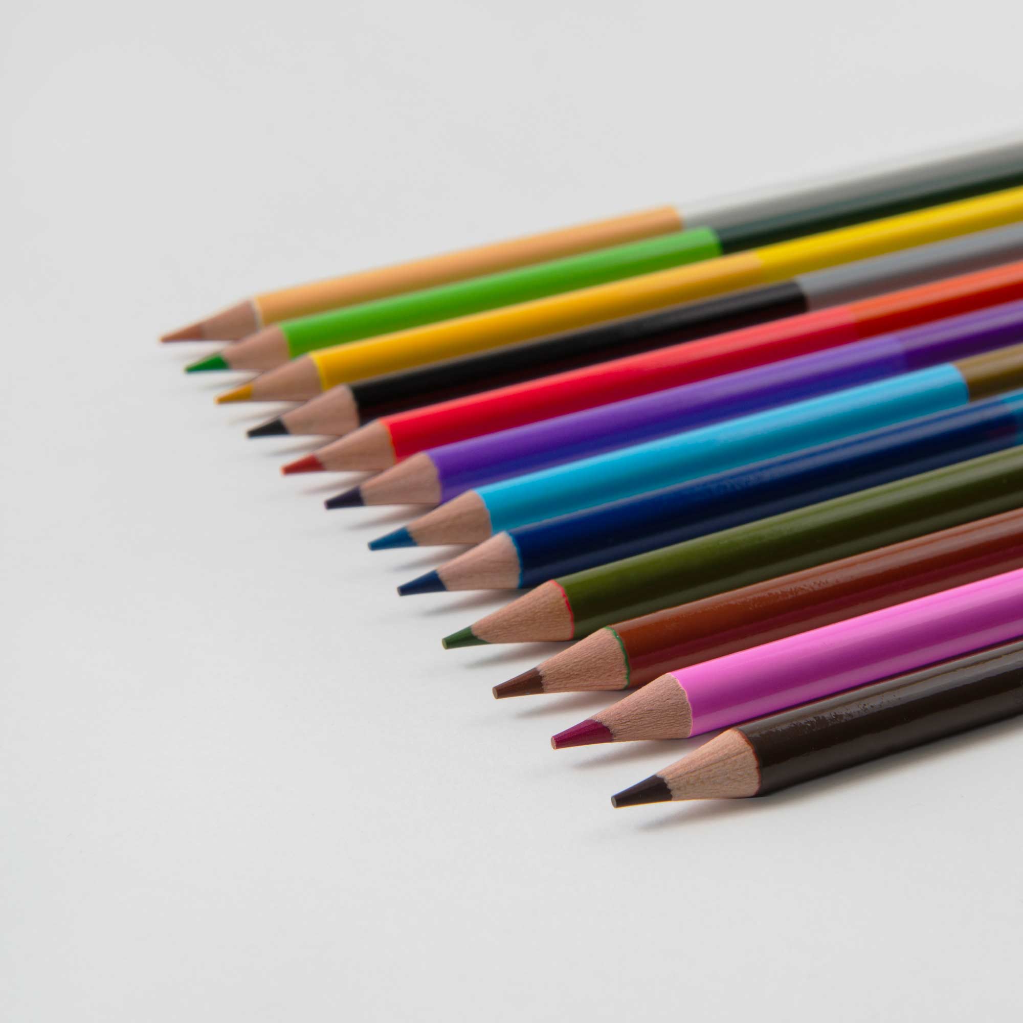 Diagonale 2-in-1 Buntstifte von Paper Poetry auf weißem Untergrund zeigen leuchtende Farben wie Grün, Gelb, Blau, Rot, Pink und Schwarz. Mit nach links zeigenden Spitzen eignen sie sich perfekt für ein Metalletui.
