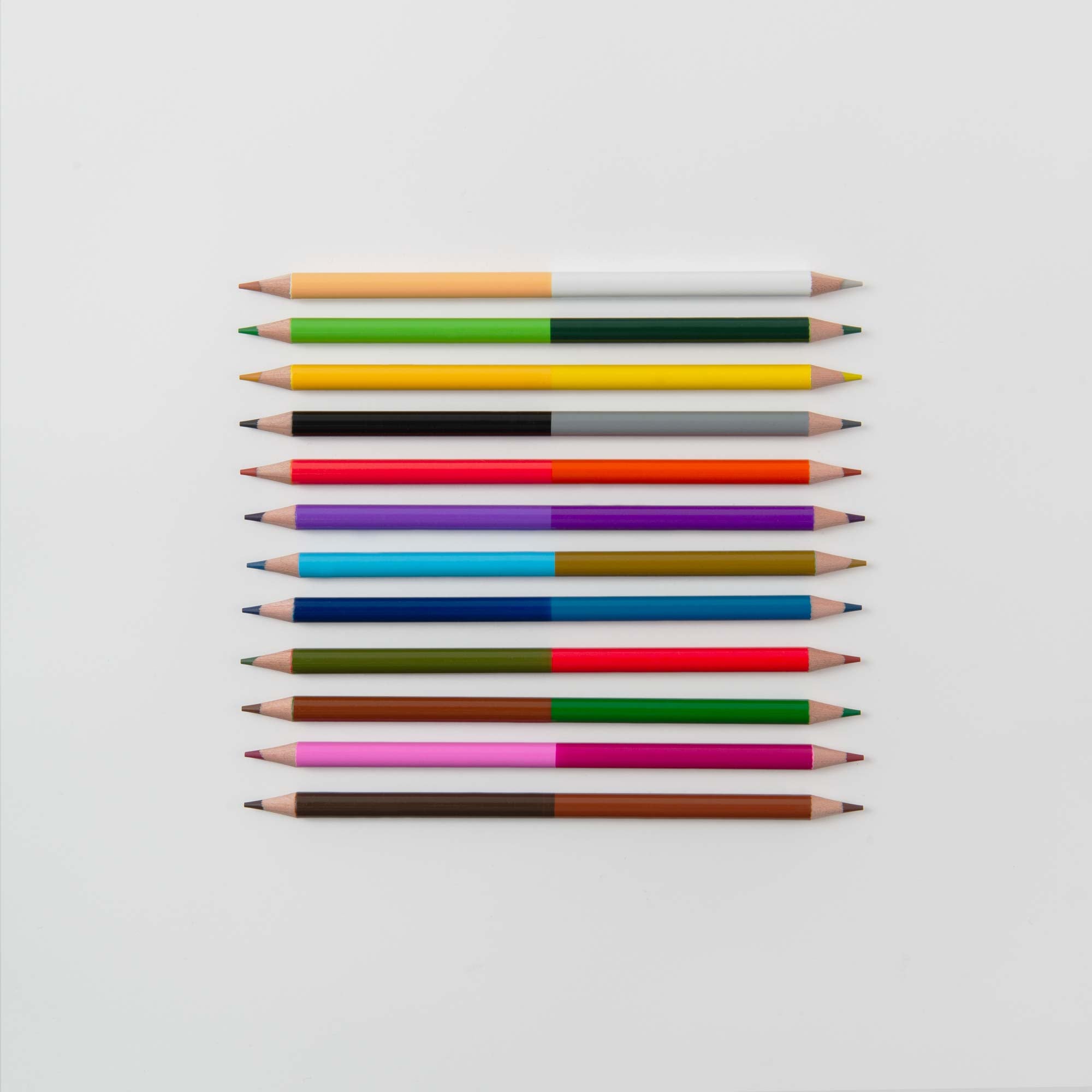 Ein Set aus zwölf farbenfrohen 2-in-1-Buntstiften im Etui von Paper Poetry wird horizontal auf einem weißen Hintergrund angezeigt, jeder weist einzigartige Farbkombinationen auf und ist in einem eleganten Metalletui untergebracht.